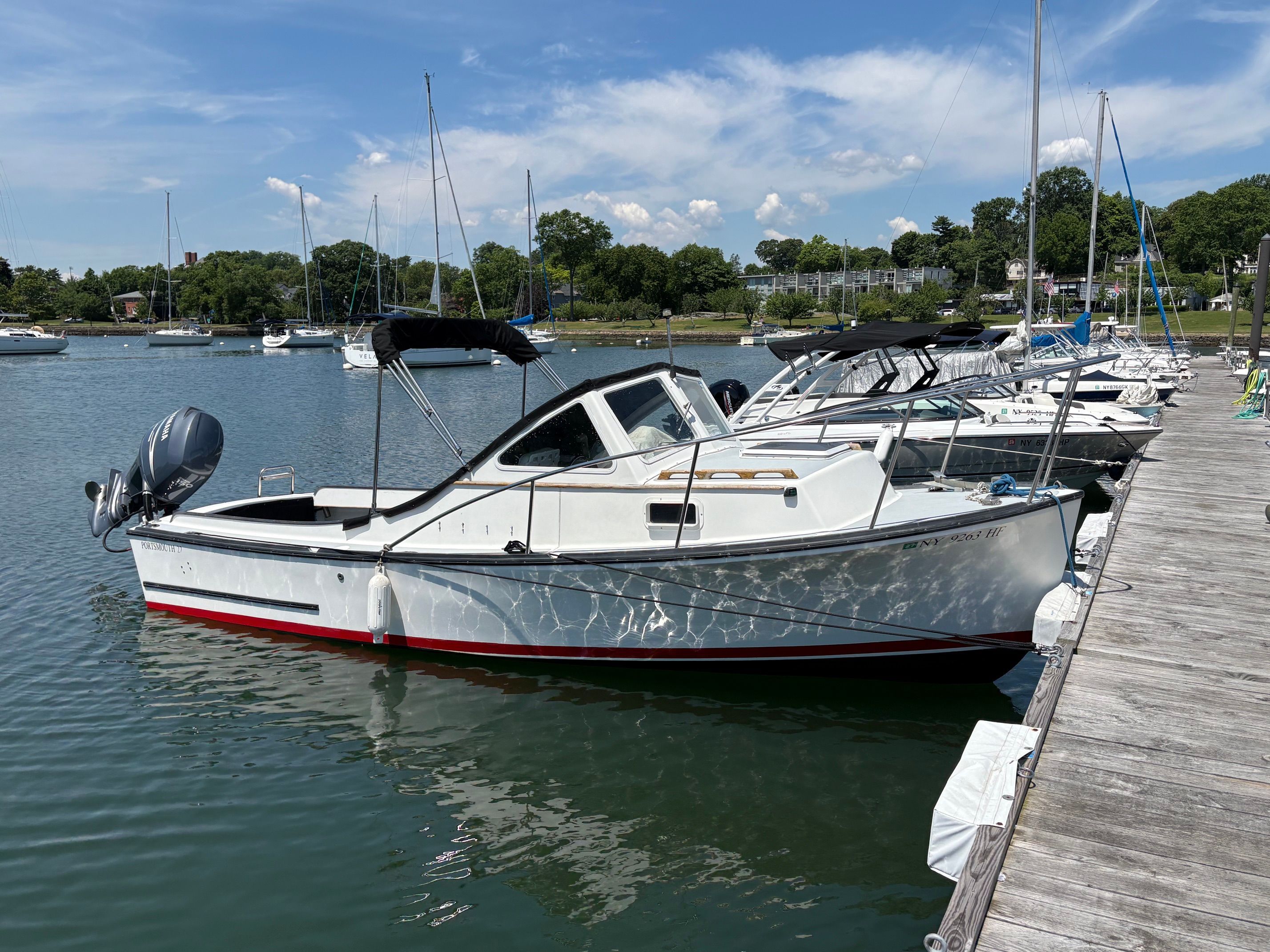 A white 1990 Portsmouth 22 boat docked in a harbor on a sunny day.