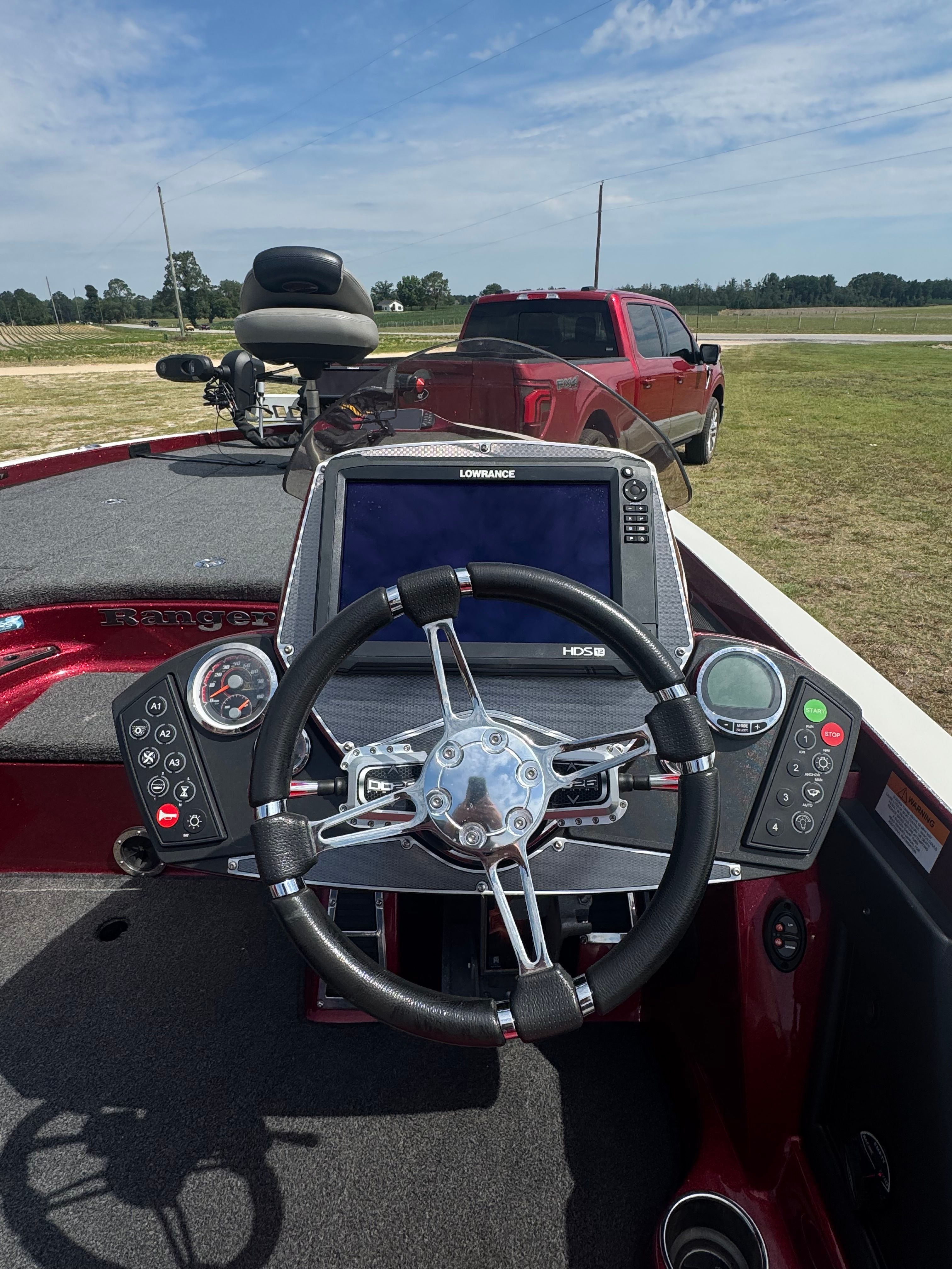 The cockpit of a red Ranger boat with steering wheel and electronics.