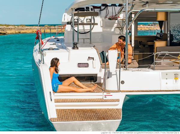 Couple relaxing on Lagoon 42 Millenium yacht, 2025 model, in clear turquoise waters.