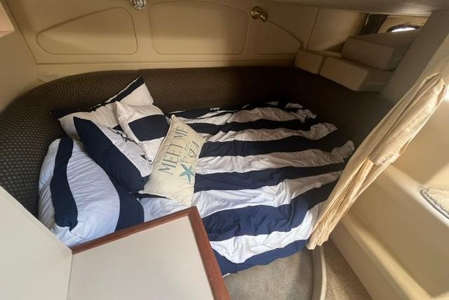 Interior cabin of 2004 Cruisers Yachts 3372 Express with striped bedding and nautical decor.