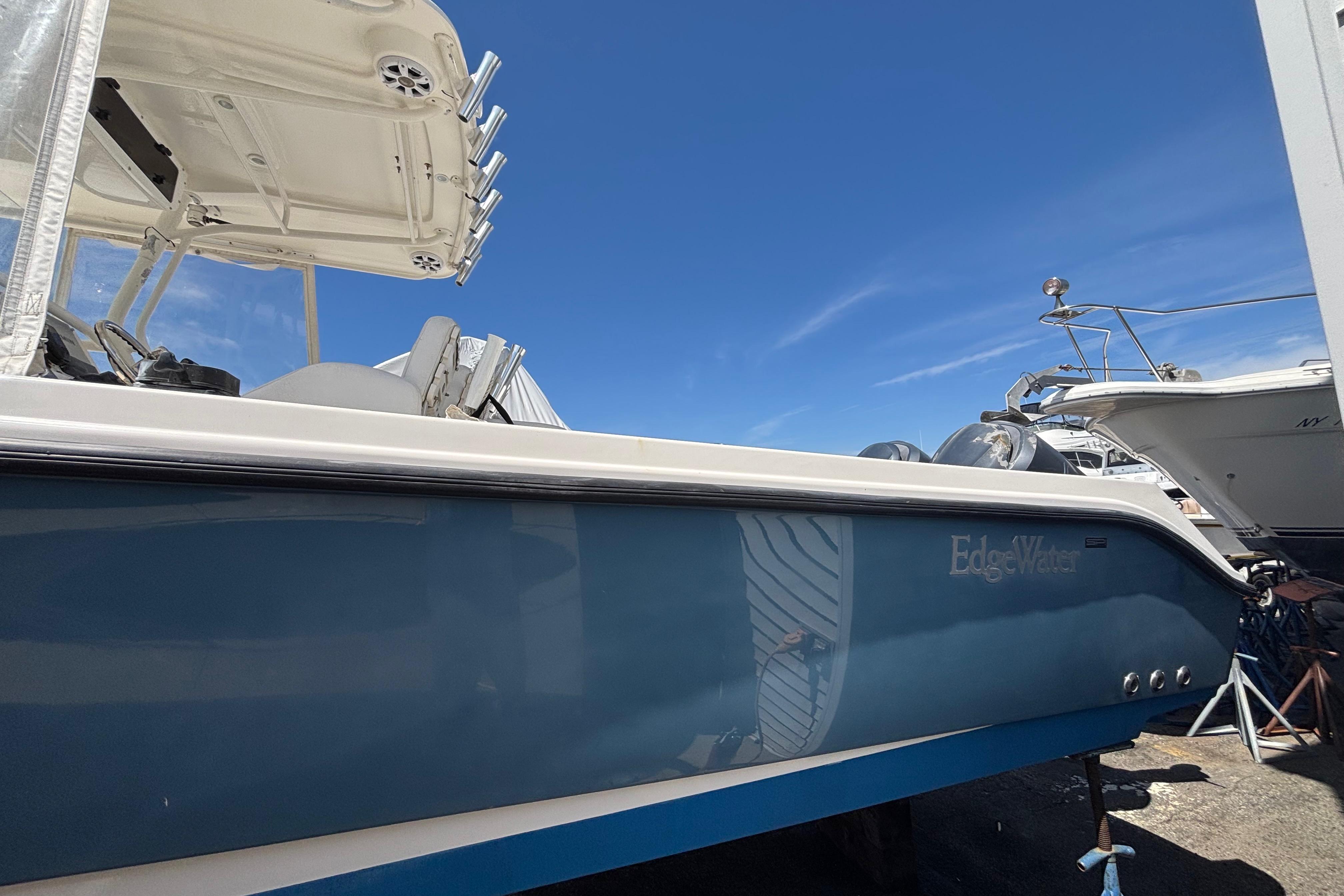 2006 Edgewater 318CC boat with blue hull, docked under clear blue sky.