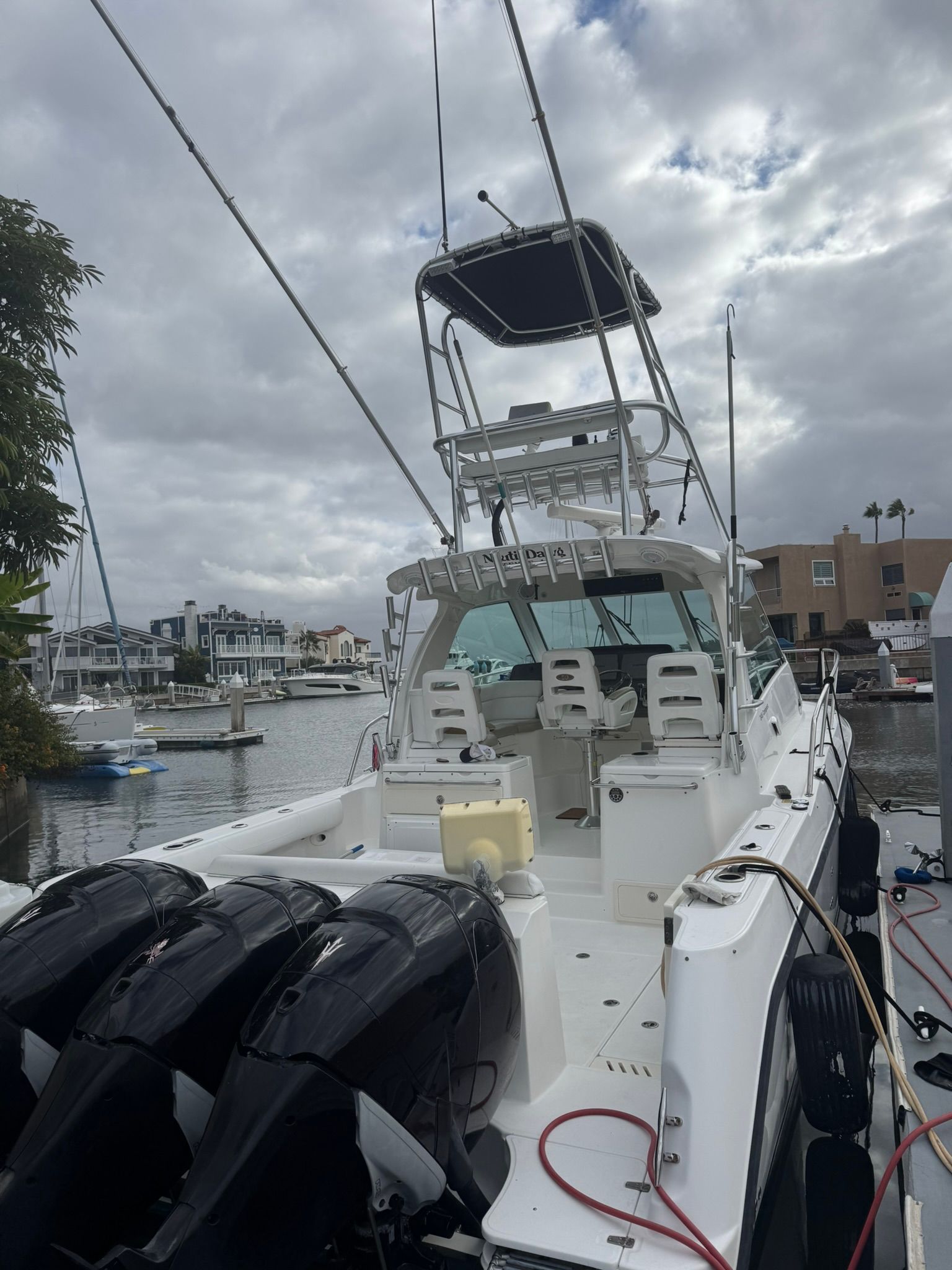 A 2008 Boston Whaler 345 Conquest docked in a marina. It features three outboard engines and a flybridge.