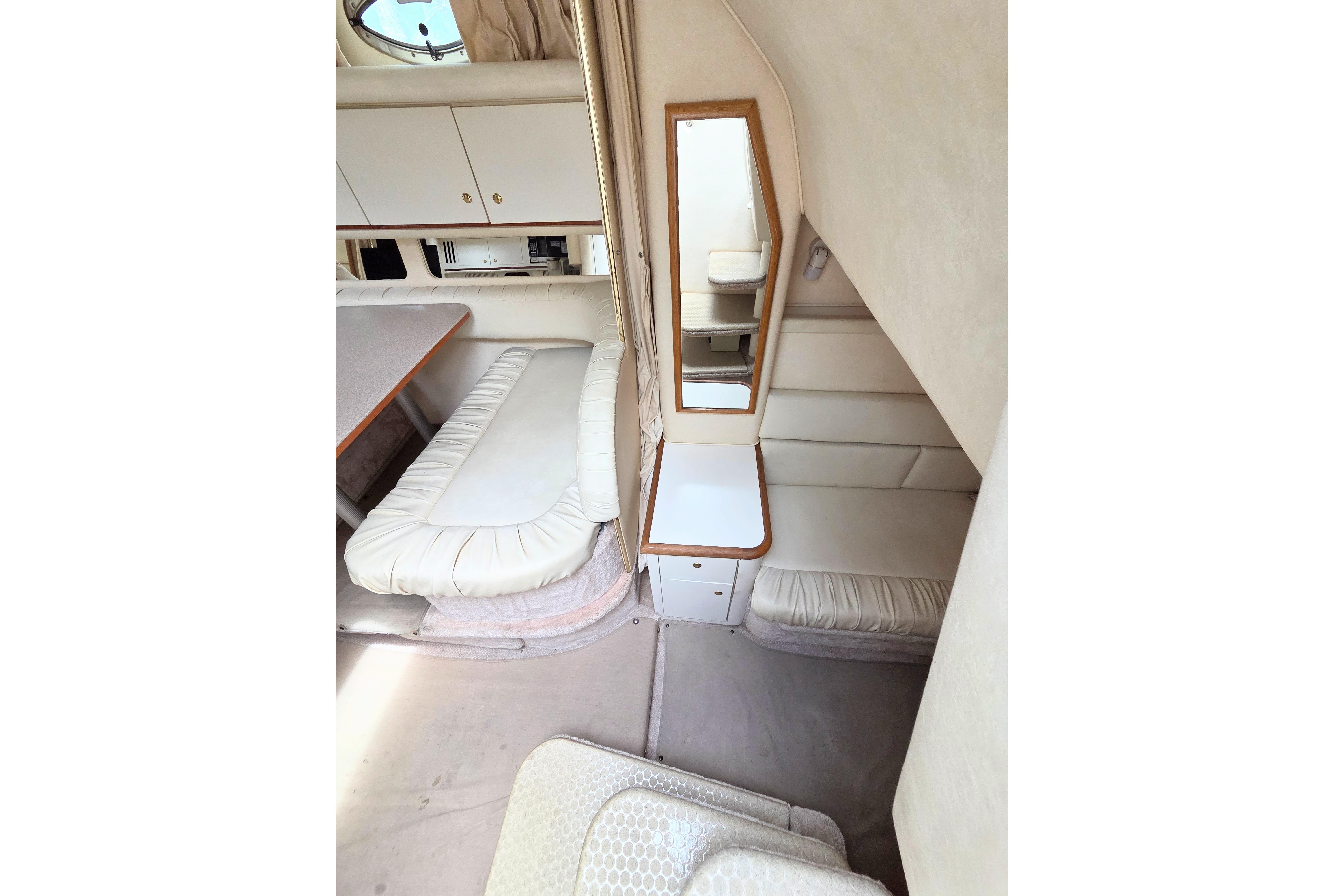 Interior of 2000 Sea Ray 340 Sundancer yacht with cozy seating and mirror.