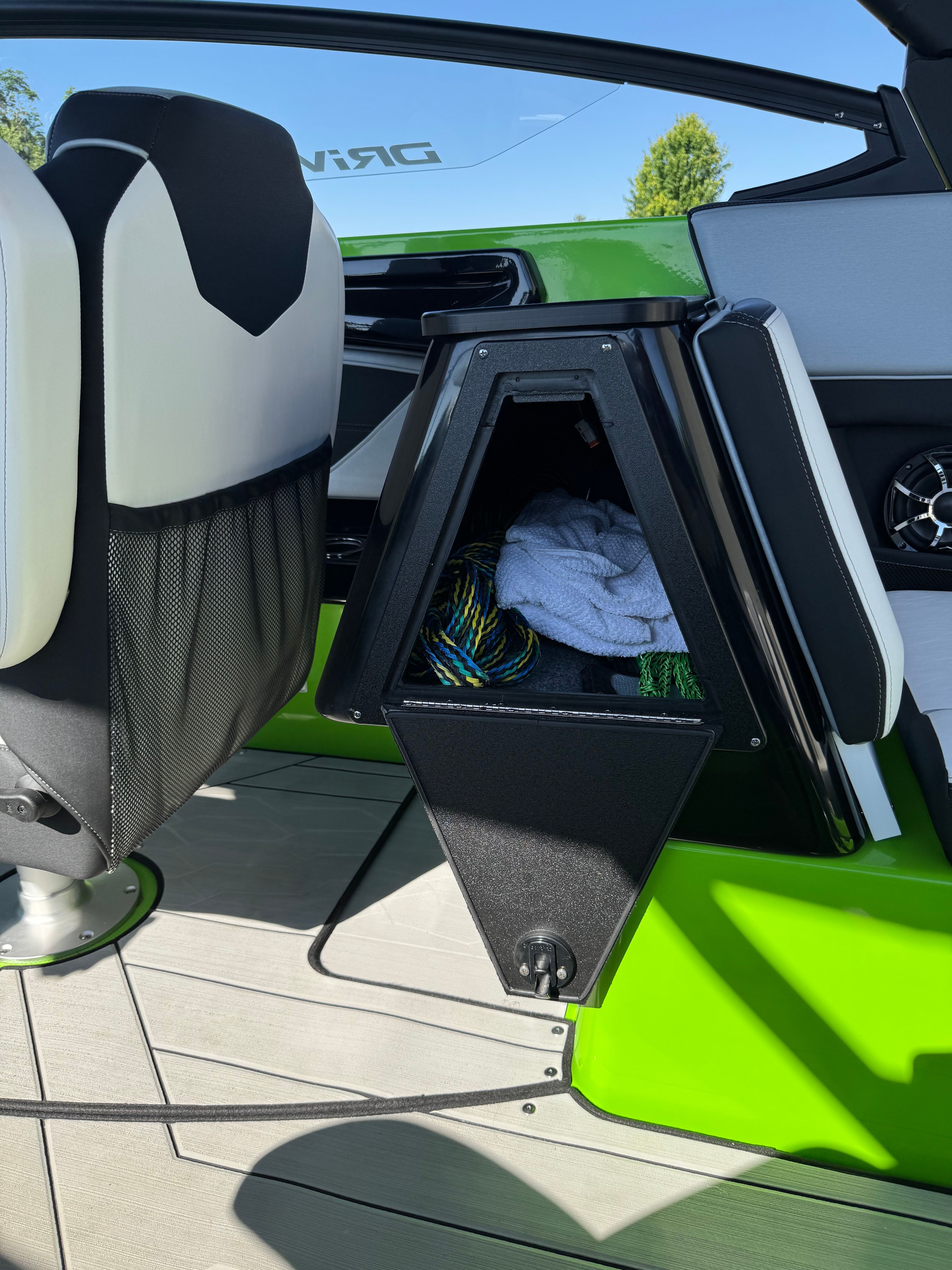 Interior of a 2022 Yamaha 255XD with green accent, storage compartment holding ropes and towel.