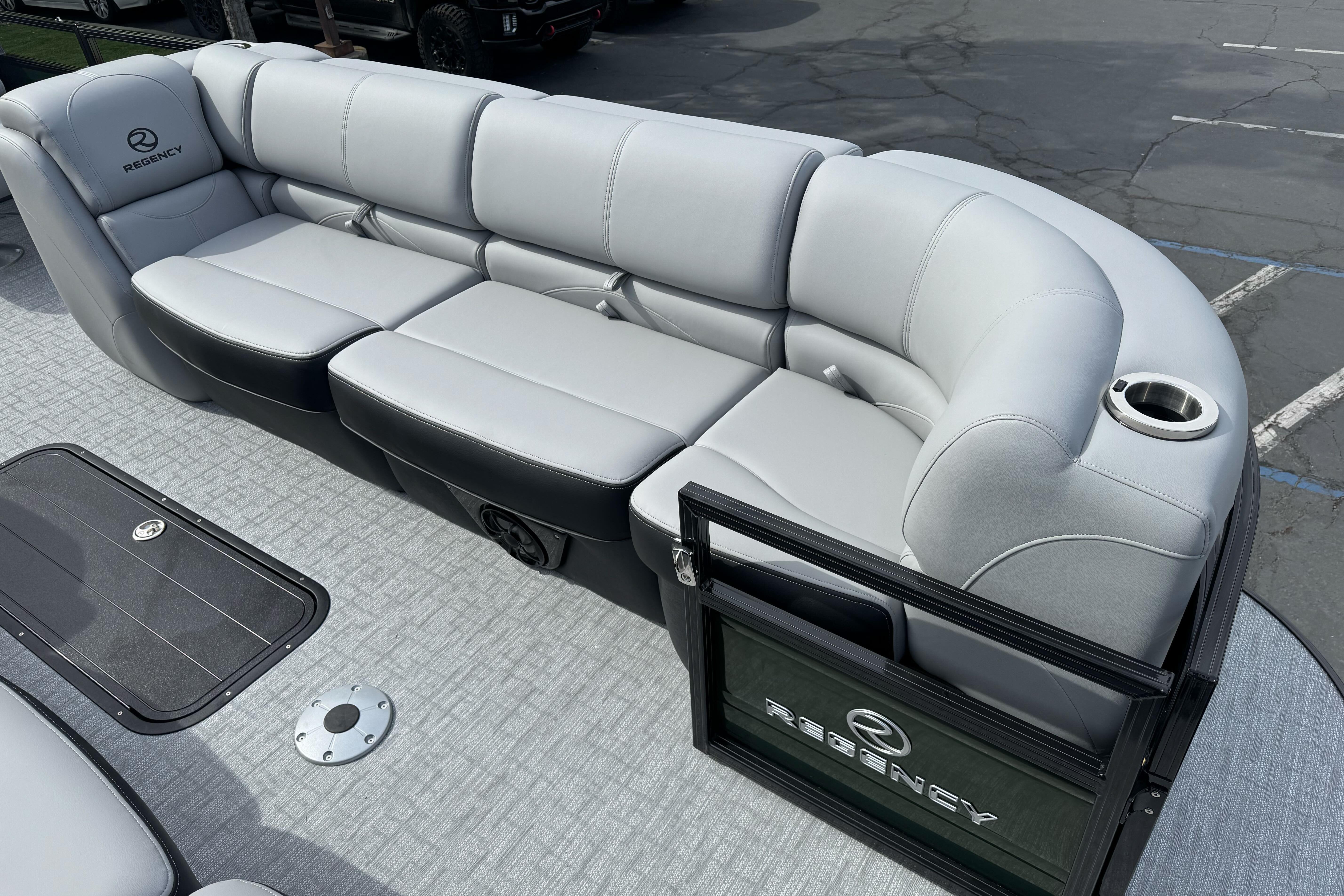 Luxurious seating on 2026 Regency 250 DL pontoon boat with cup holder and branded gate.