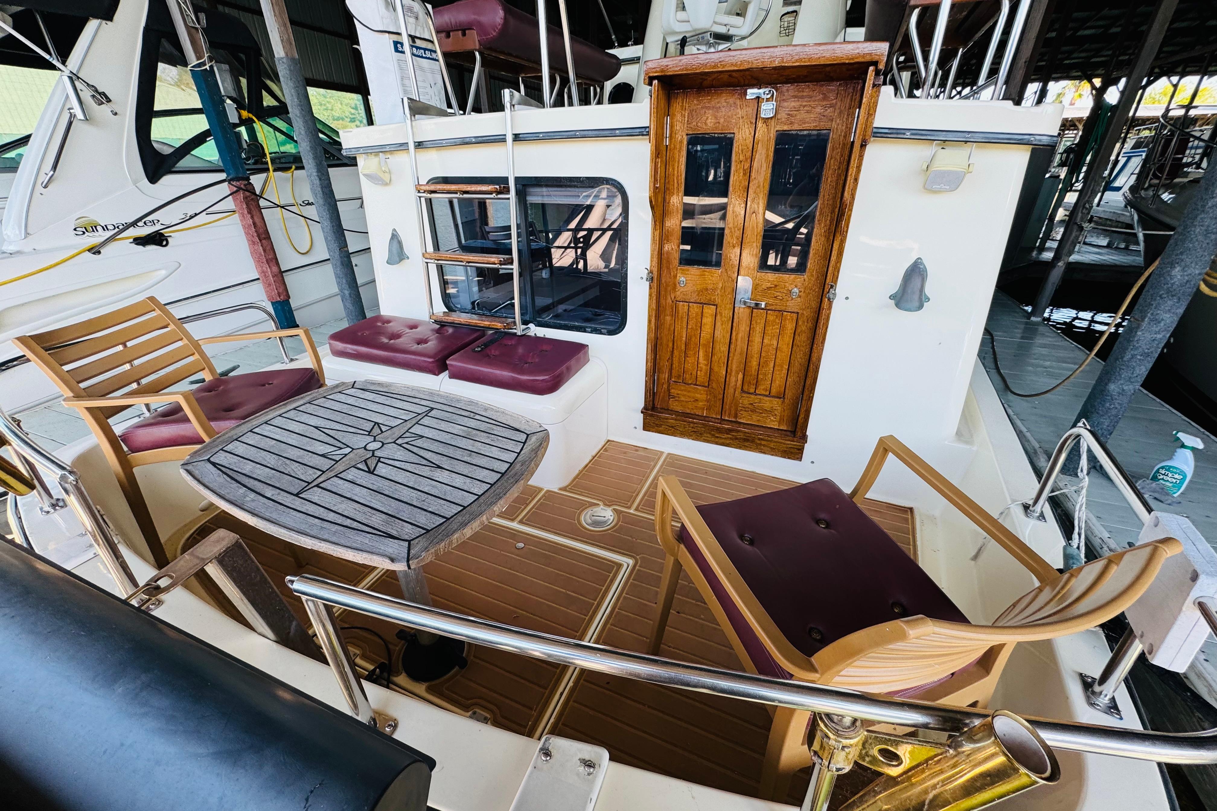 1996 Nordic Tug 32 boat with wooden deck, chairs, and table in a marina setting.