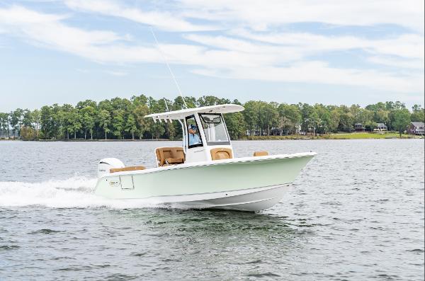 2025 Sea Hunt Ultra 235 SE boat cruising on a lake with trees in the background.