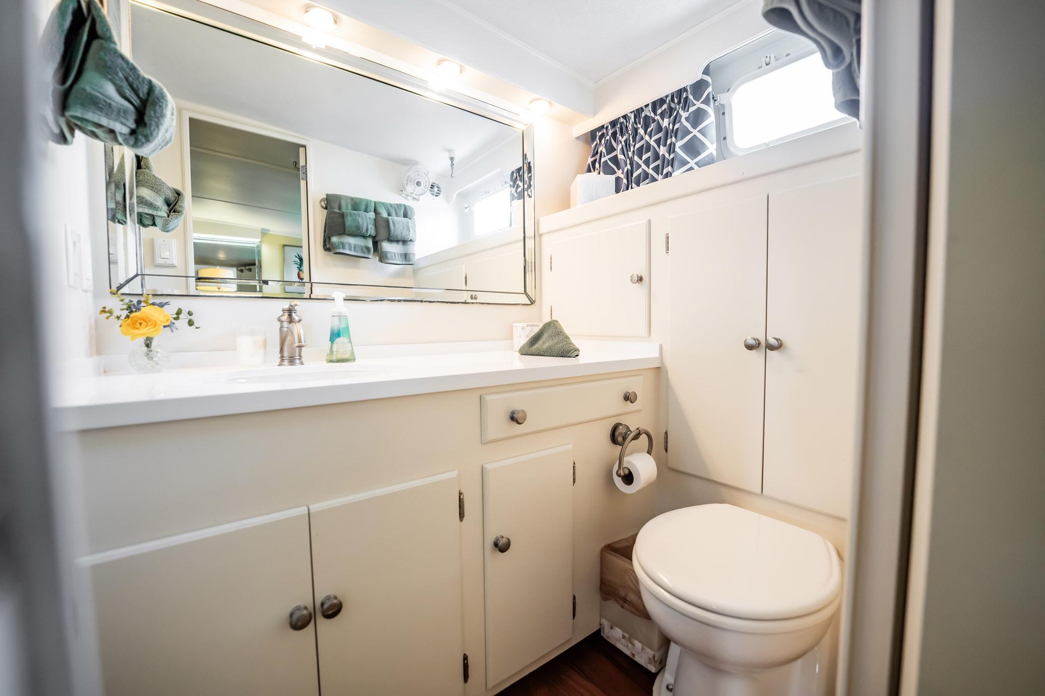 Bathroom interior of 1972 Trumpy 72 Motor Yacht with white cabinetry and mirror.