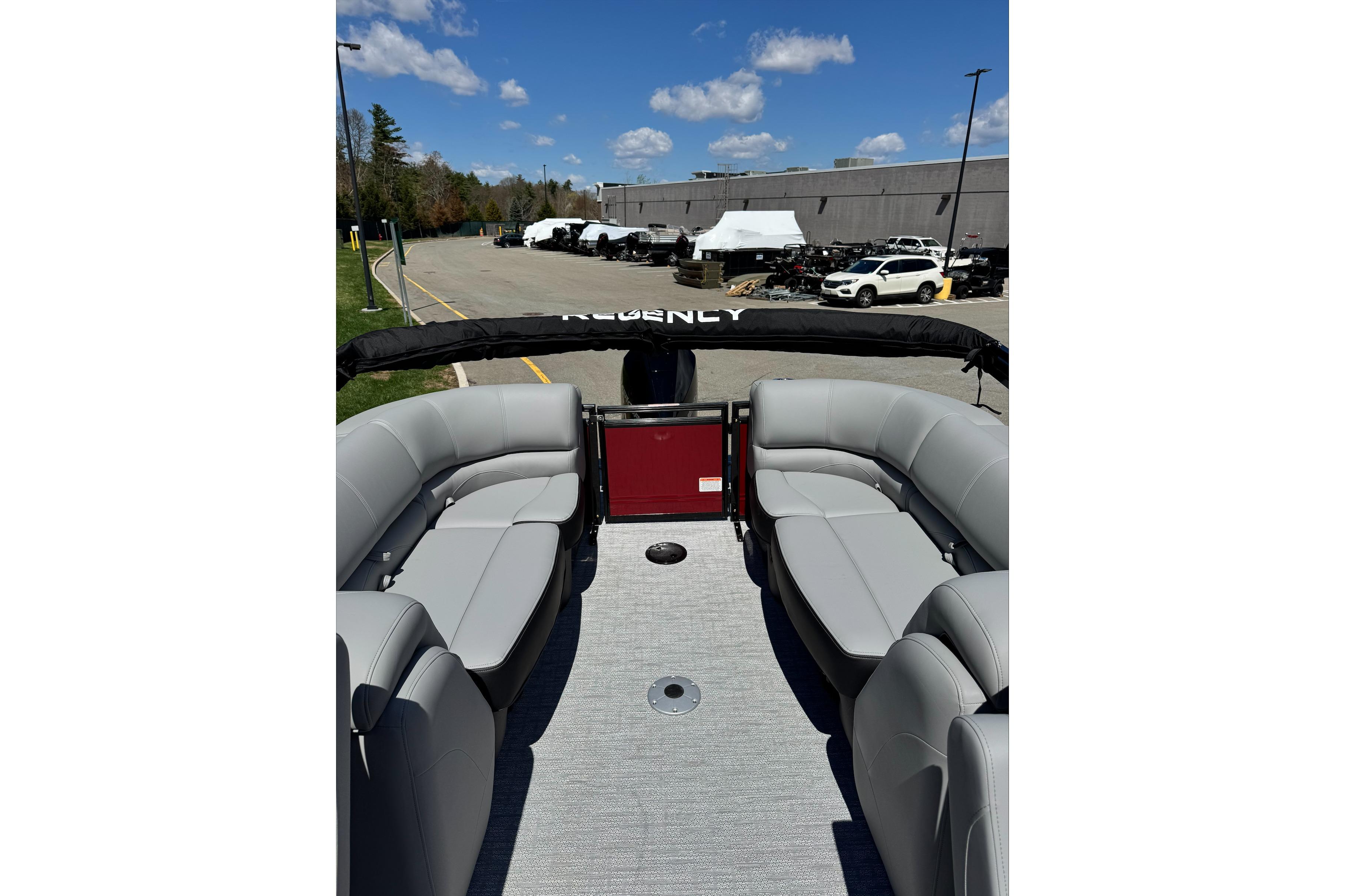 2026 Regency 230 DL pontoon boat with gray seating, parked outdoors under blue sky.