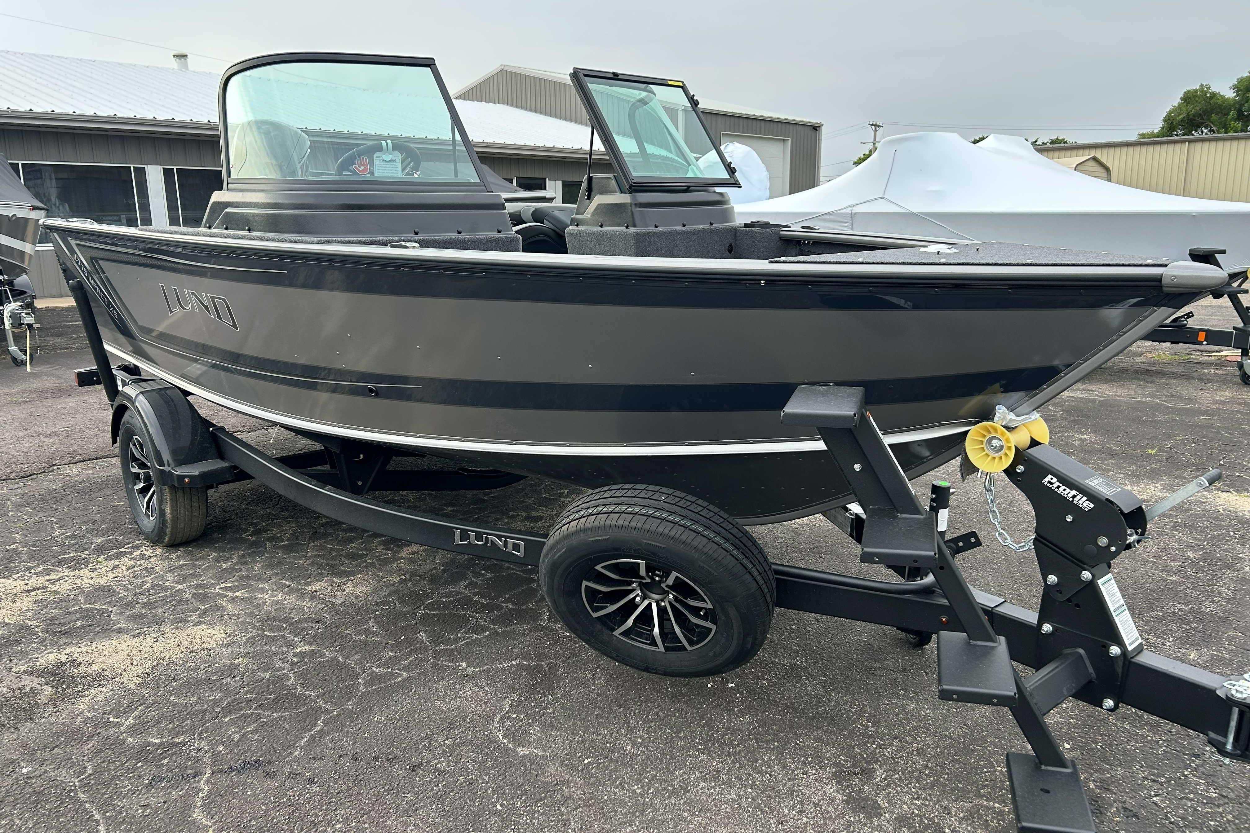 2027 Lund 1775 Impact XS boat on trailer, parked outdoors.