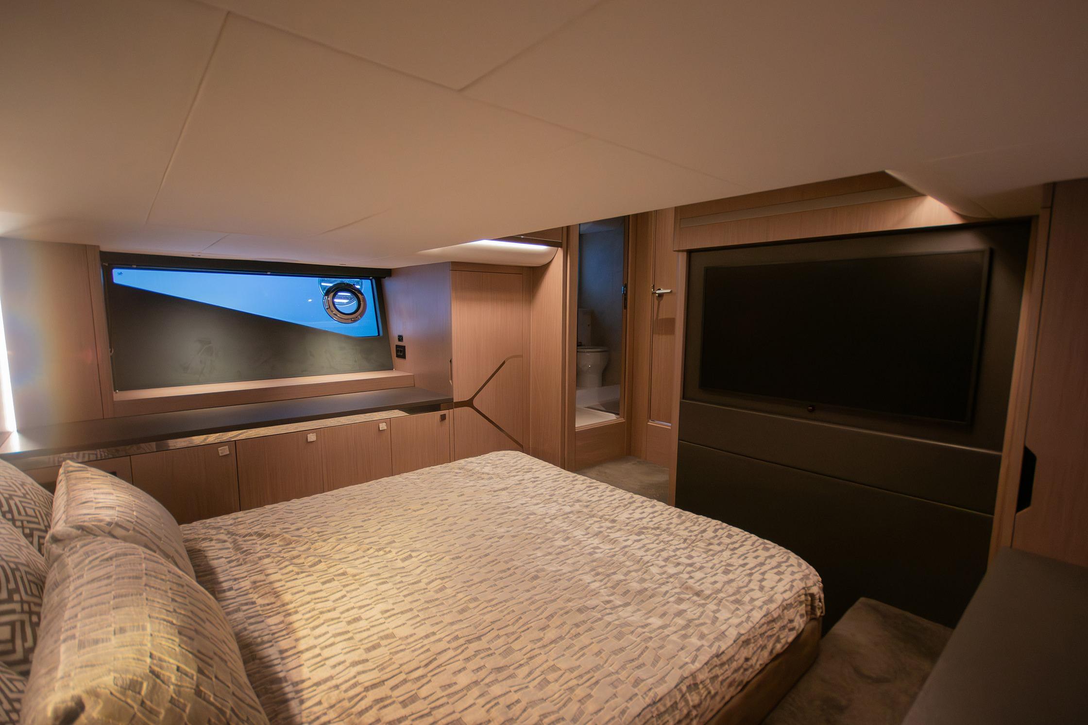 Luxurious 2024 Sunseeker Superhawk 55 yacht bedroom with modern decor and large TV.