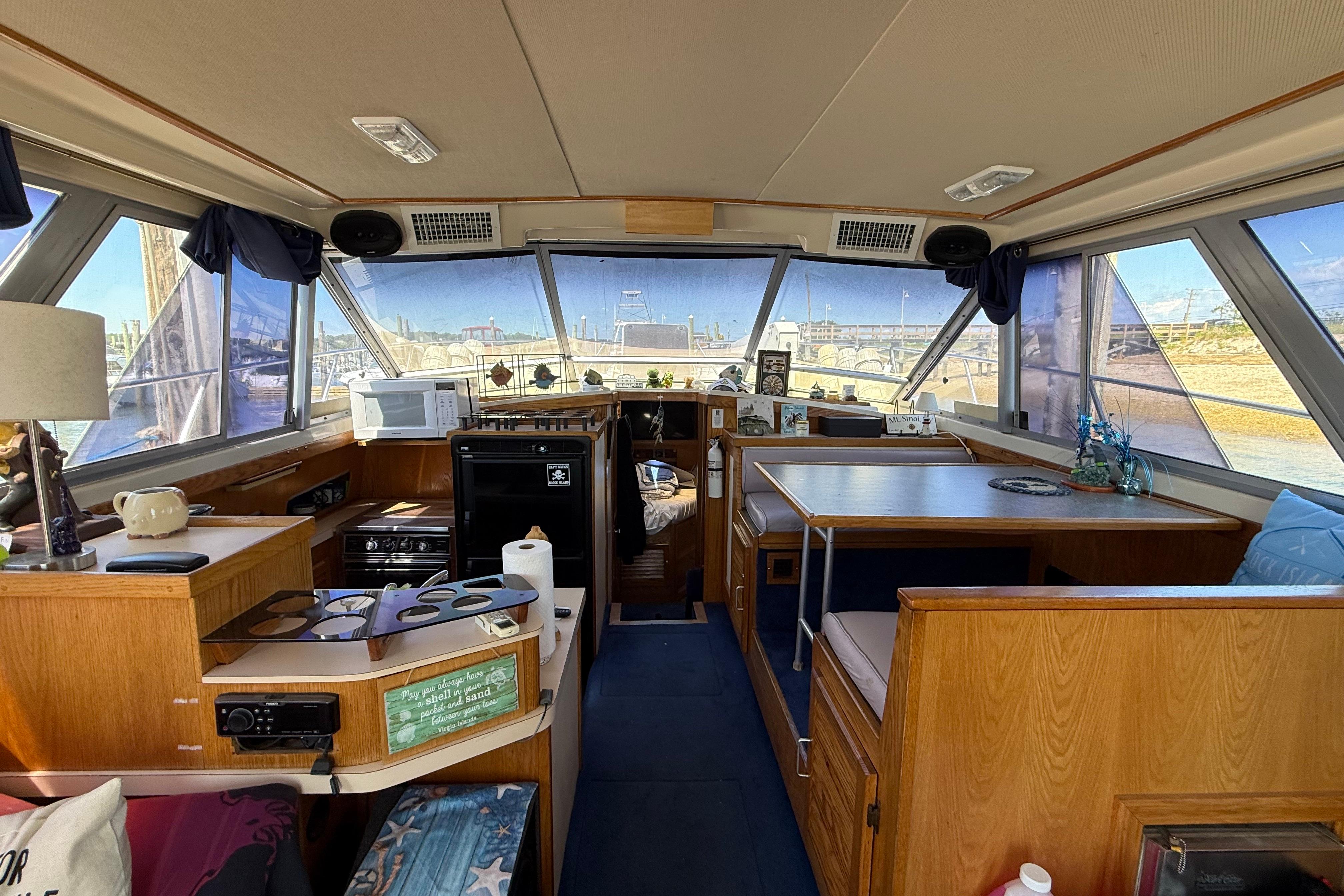 Interior of a 1986 Silverton 40 Convertible yacht with wood furnishings and panoramic windows.