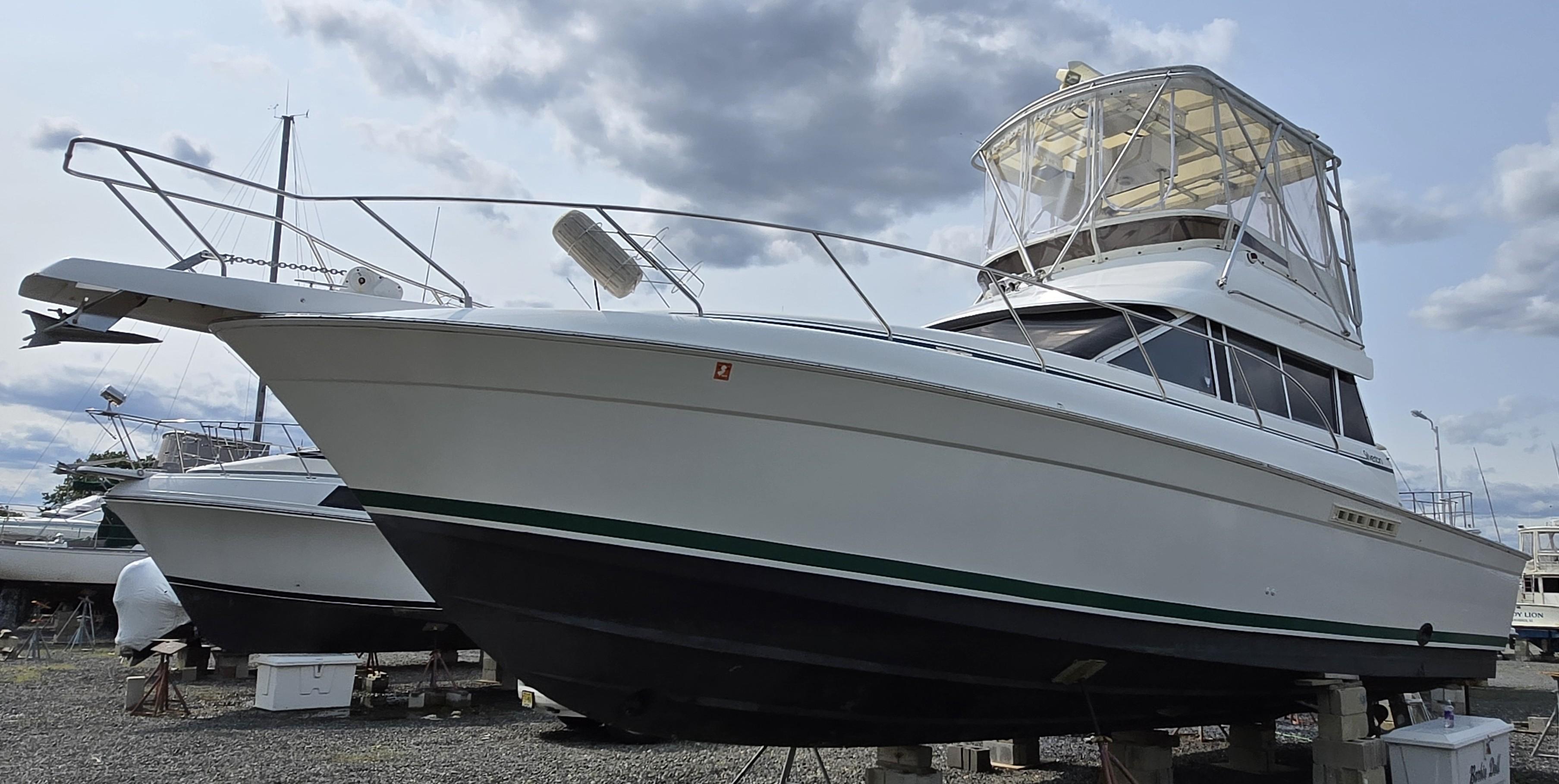 1996 Silverton 37 Convertible boat on dry dock under cloudy sky.
