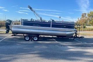 2026 Sun Tracker SportFish 22 XP3 pontoon boat on trailer in parking lot.