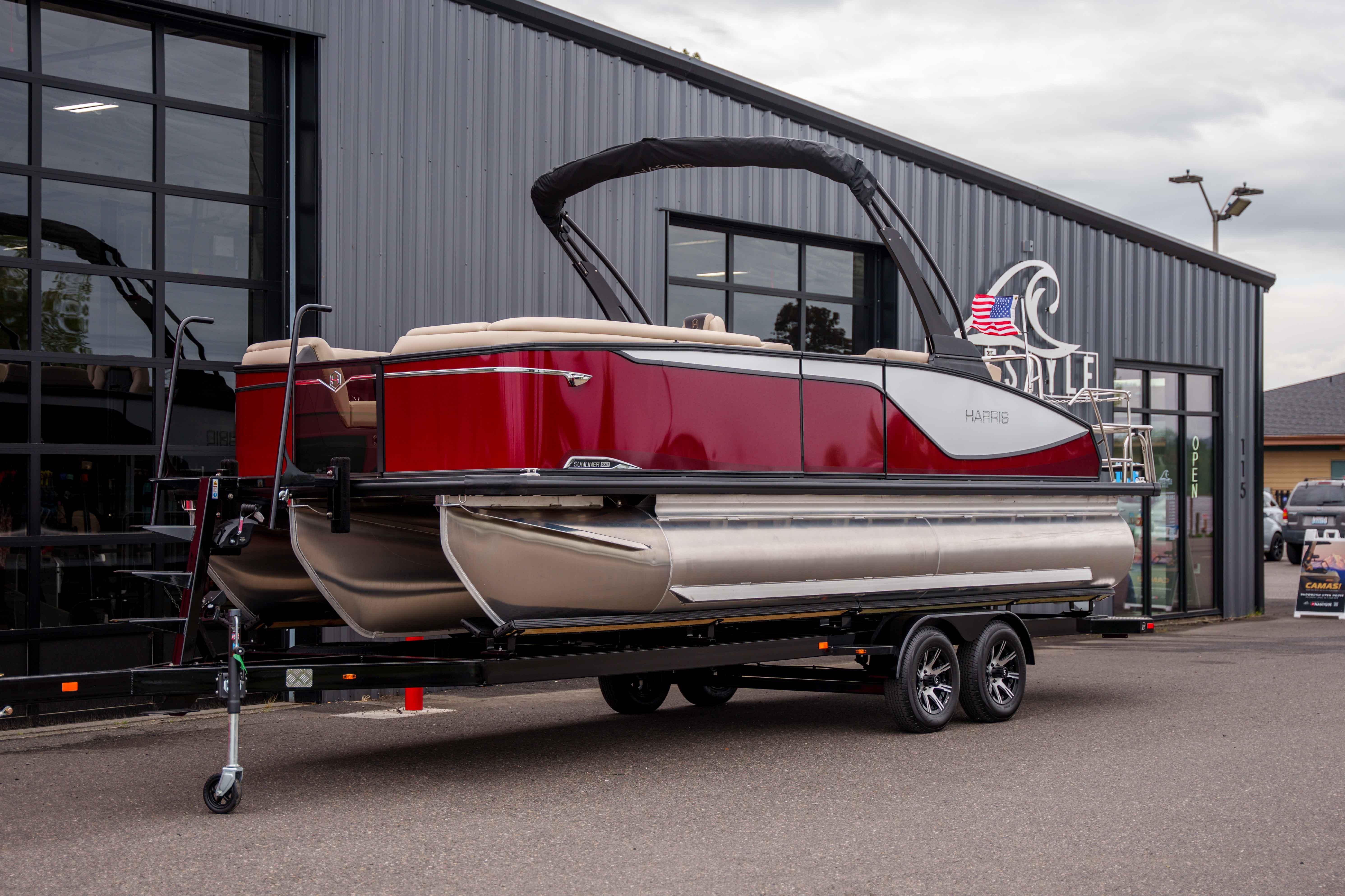 2026 Harris Sunliner 230 pontoon boat on trailer outside dealership.