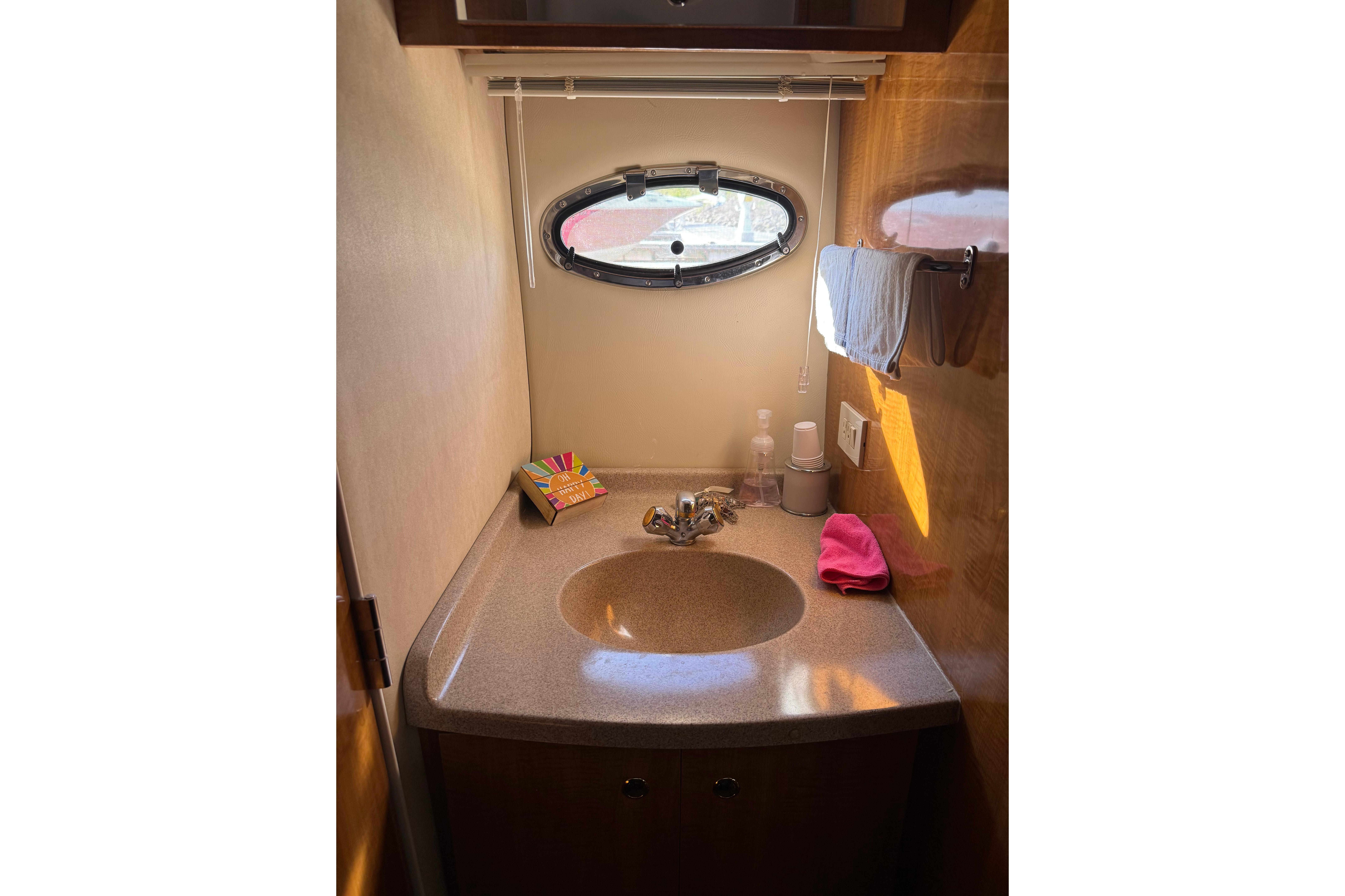 Bathroom sink area in a 2007 Regal Commodore 3860 yacht, featuring a porthole window.
