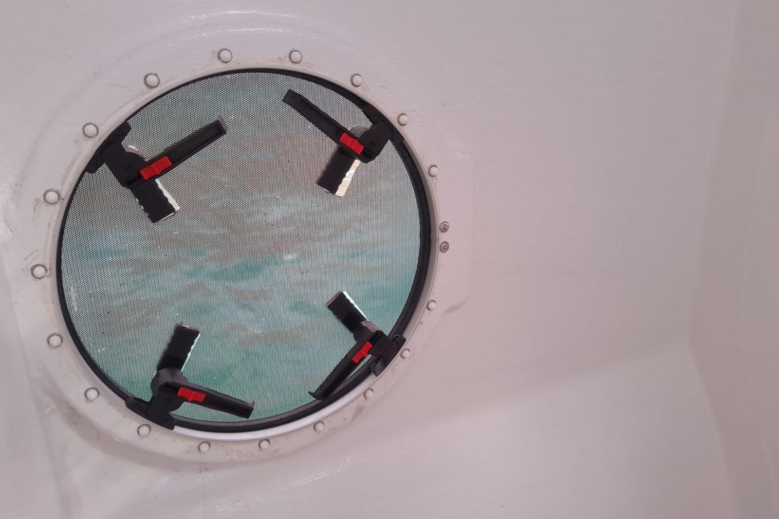Round window with clamps on a 2019 Marsaudon Composites TS5 catamaran.