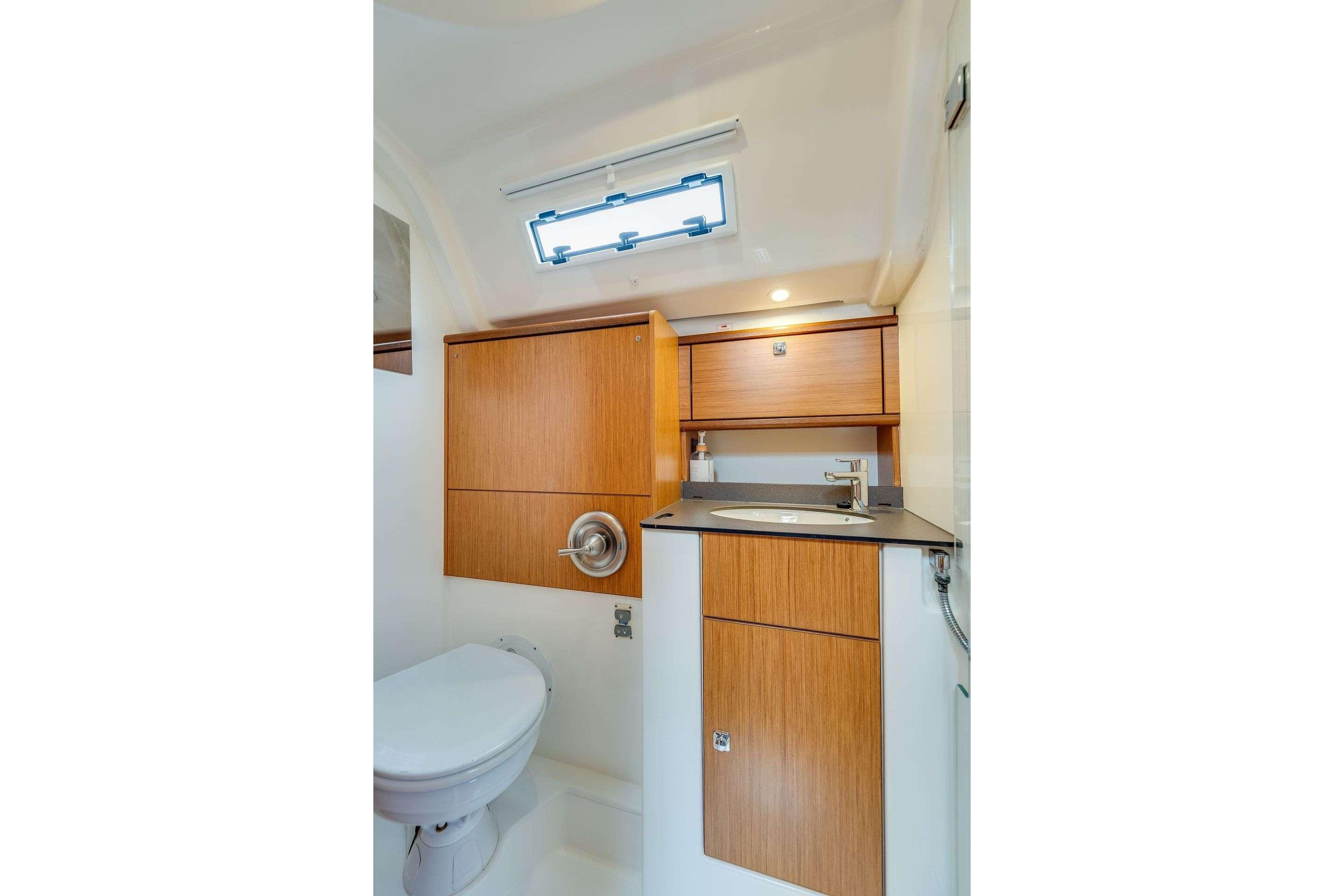 Modern bathroom interior of 2016 Bavaria 51 Cruiser yacht with wooden cabinetry and sleek fixtures.