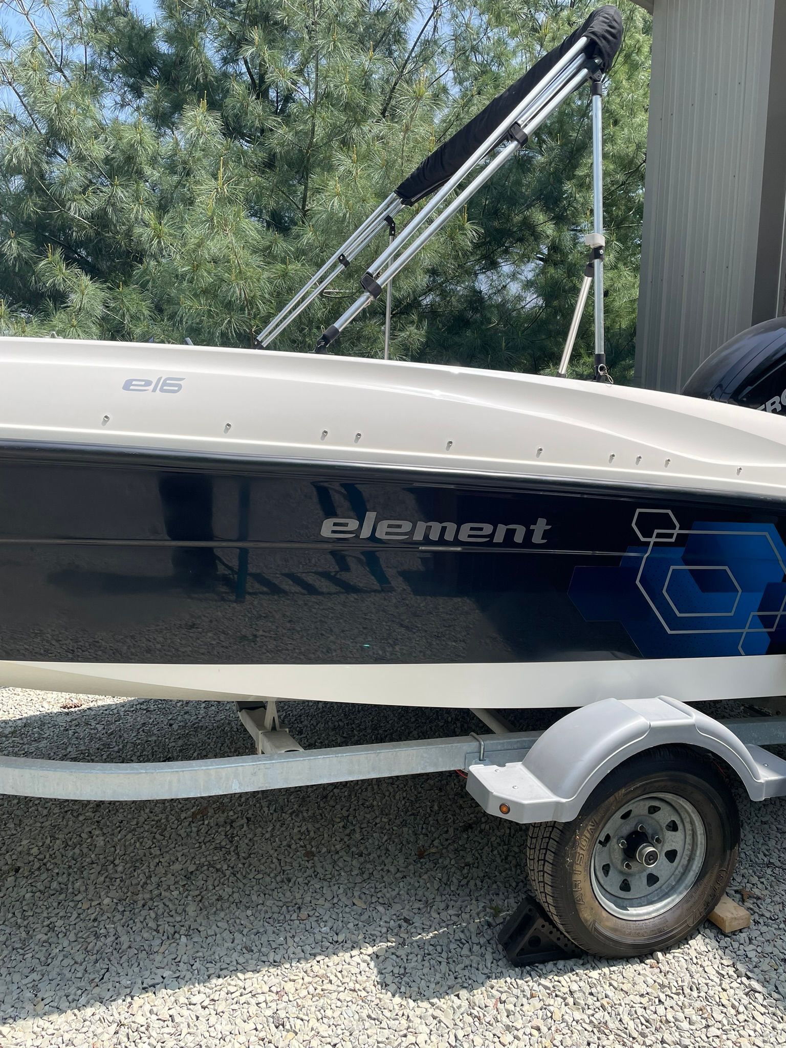 A 2018 Bayliner 160 Bowrider on a trailer, surrounded by trees.