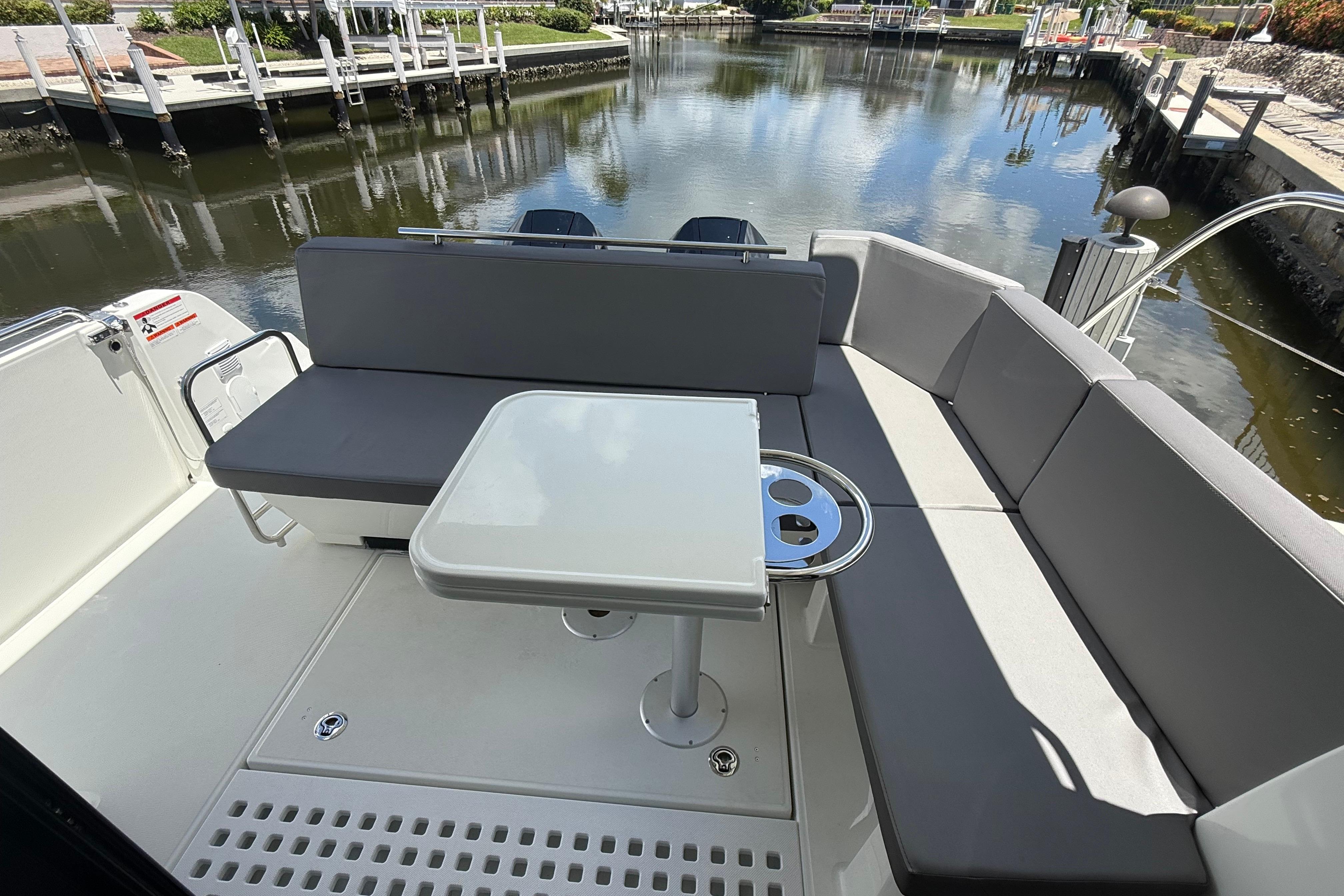 2024 Beneteau Antares 11 boat interior with seating and table, docked by a calm waterway.