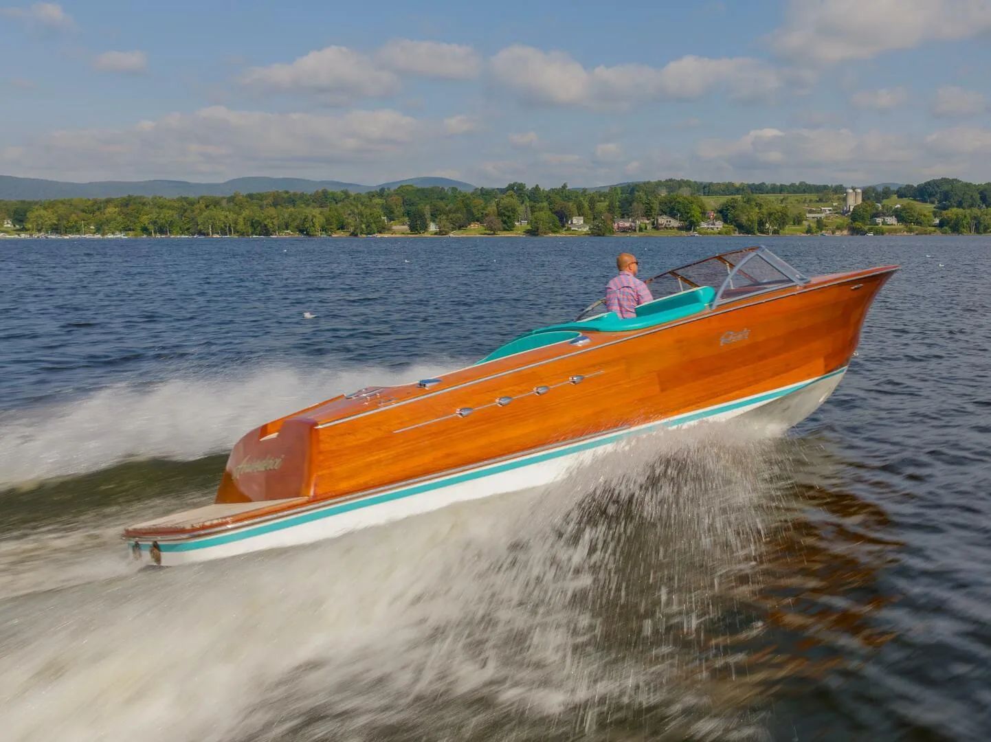 Riva Reets Aquarama 2018 cruising on a lake under sunny skies.