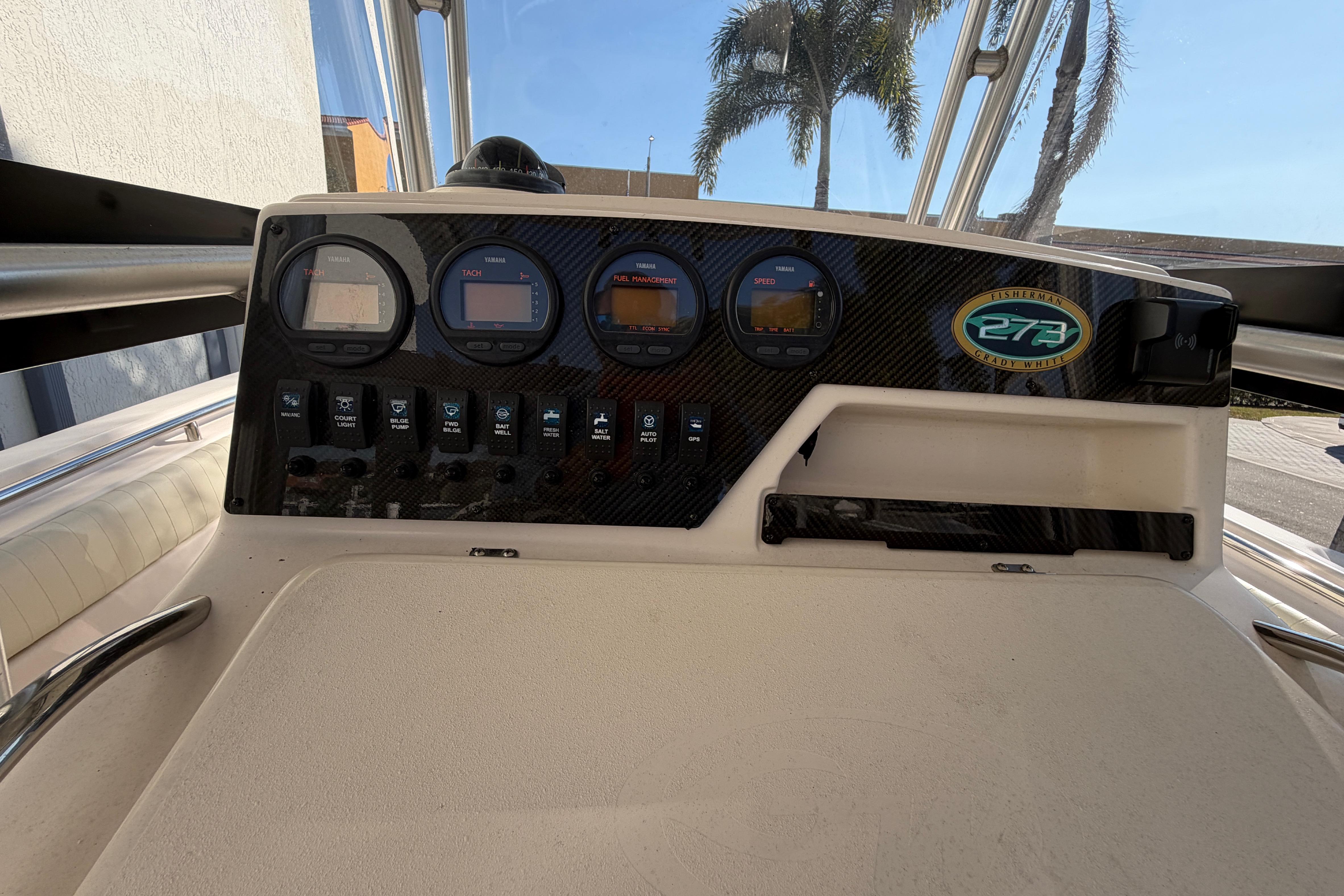 2004 Grady White 273 boat dashboard with gauges and controls, palm trees in background.