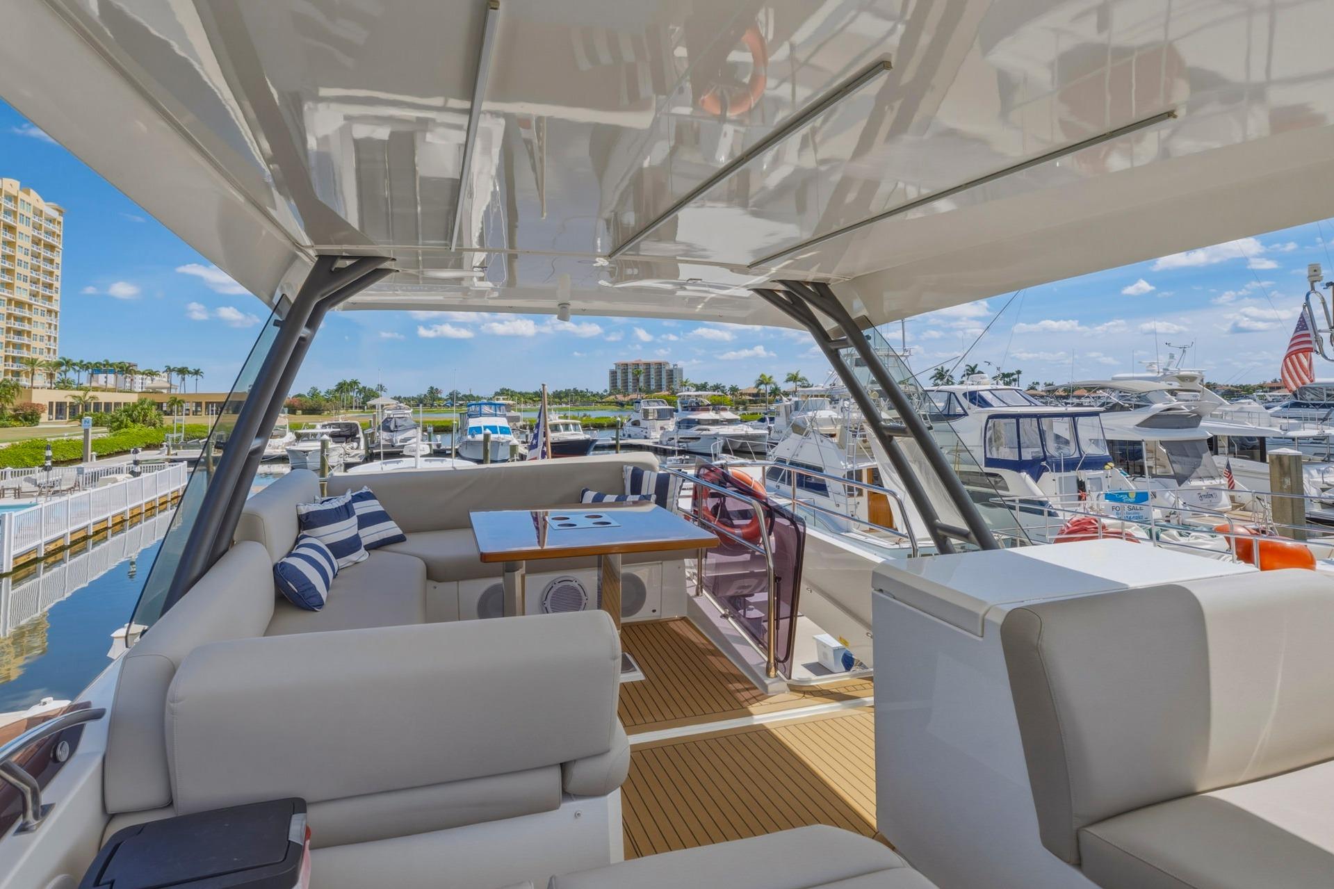 Luxurious 2022 Prestige 520 yacht interior with marina view, featuring elegant seating and table.
