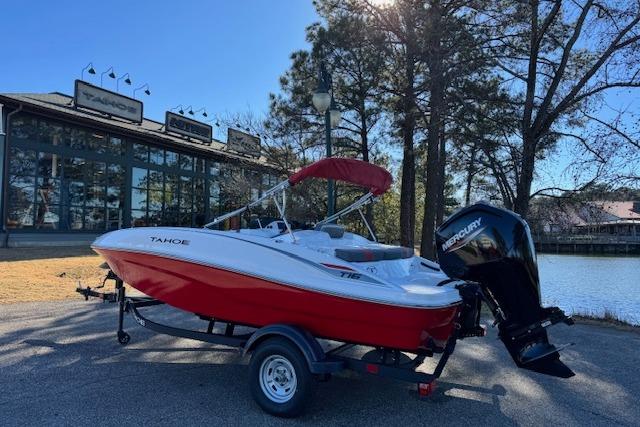 2026 Tahoe T16 boat with red hull and Mercury outboard motor, parked near a lake.