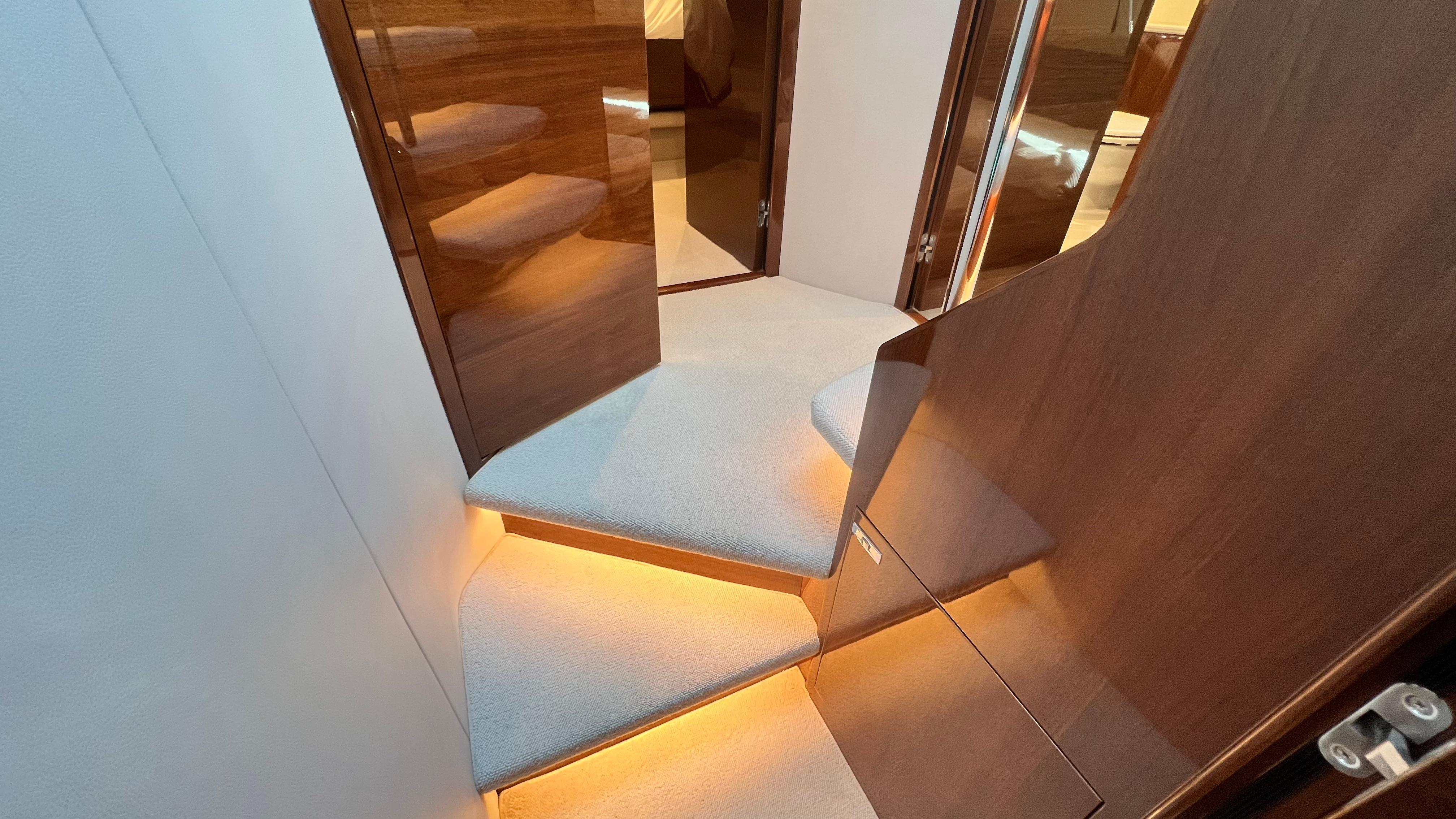 Luxurious interior staircase of 2019 Princess F62 yacht with elegant lighting.