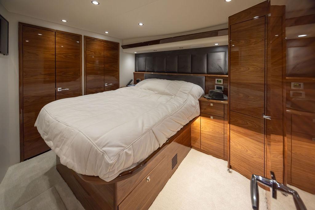 Luxurious bedroom interior of 2024 Viking 58 Convertible yacht with wood paneling and plush bedding.