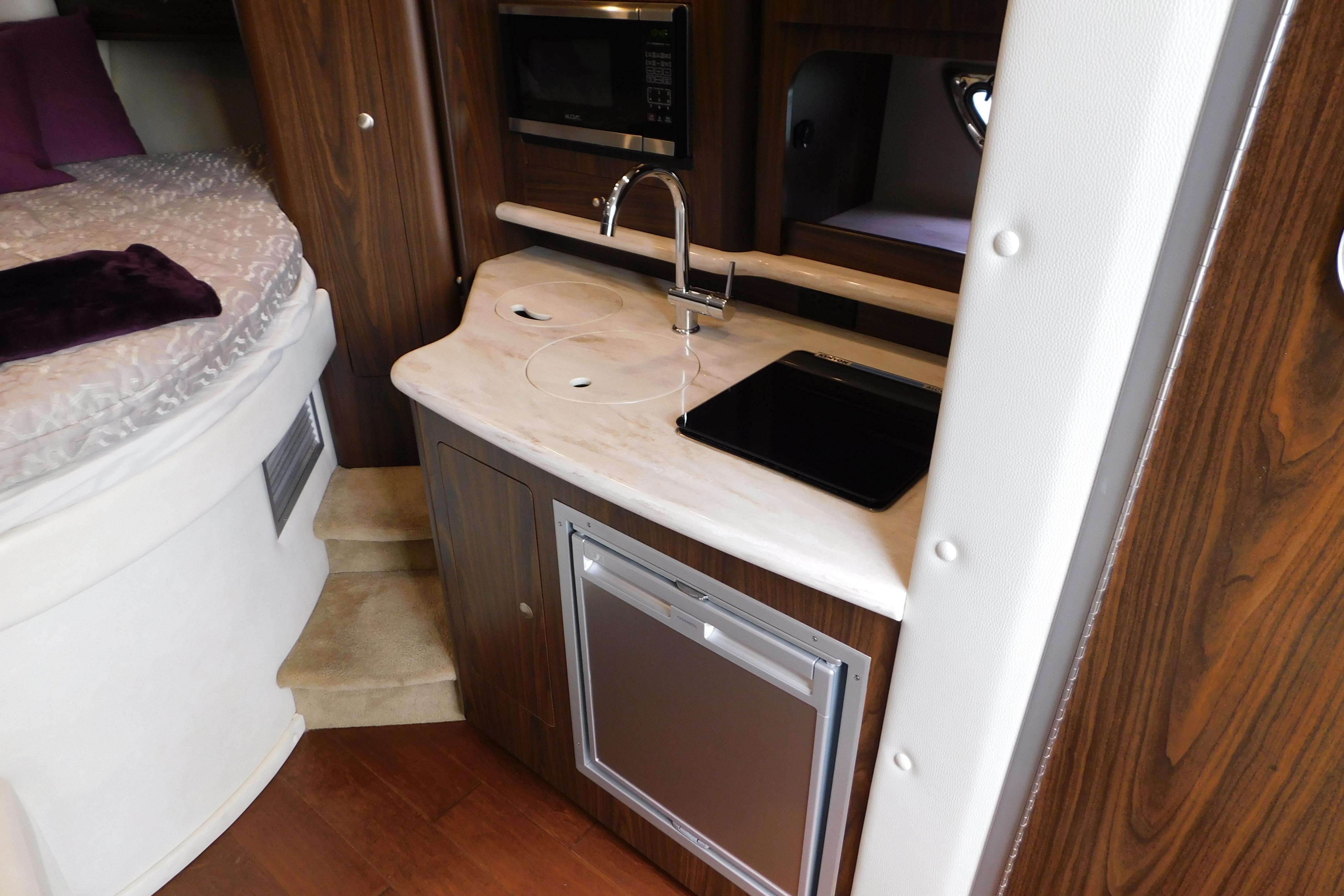 2017 Rinker EX 320 interior with kitchenette, sink, and bed.