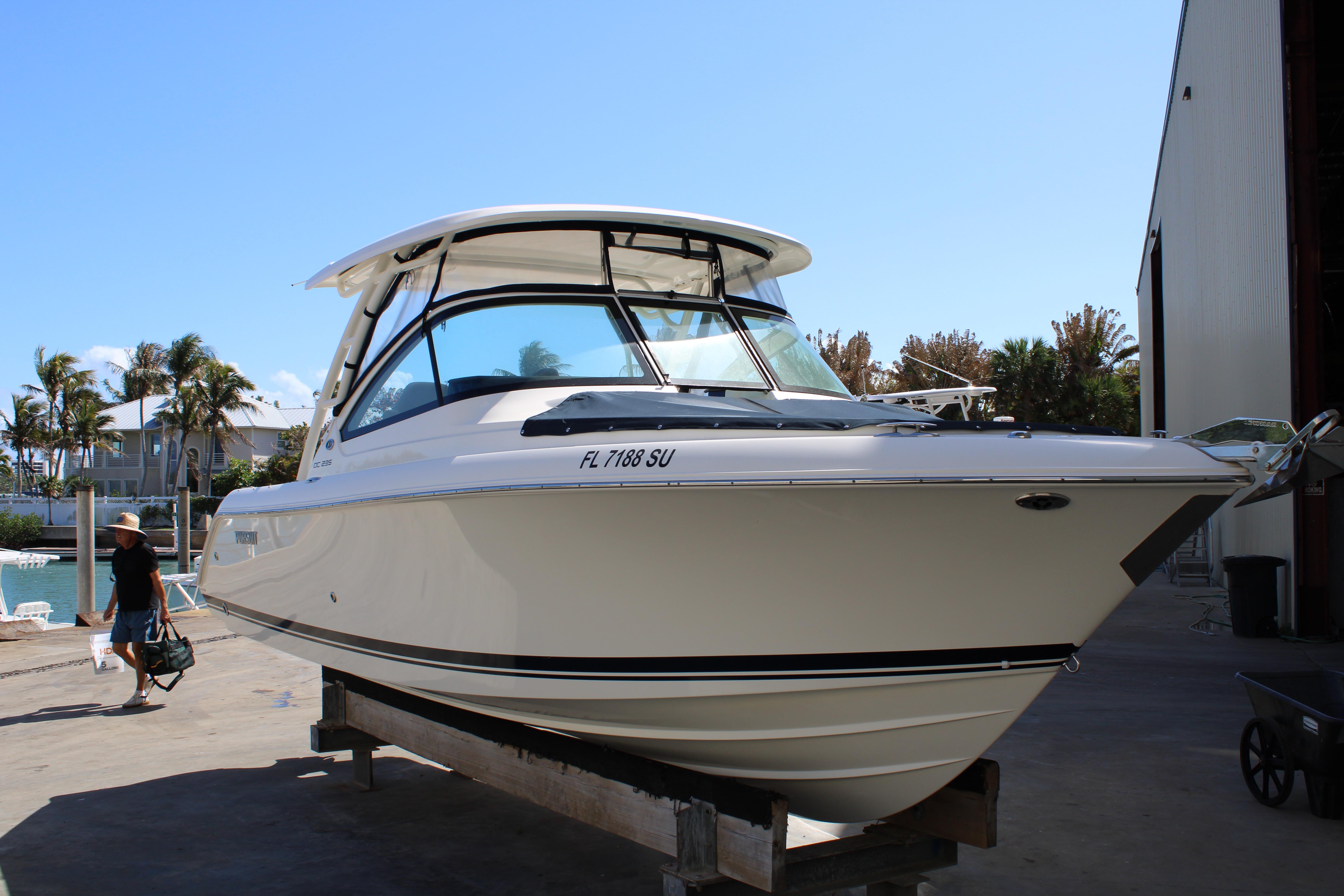 2020 Pursuit DC 235 Dual Console boat on dock, sunny day, palm trees in background.