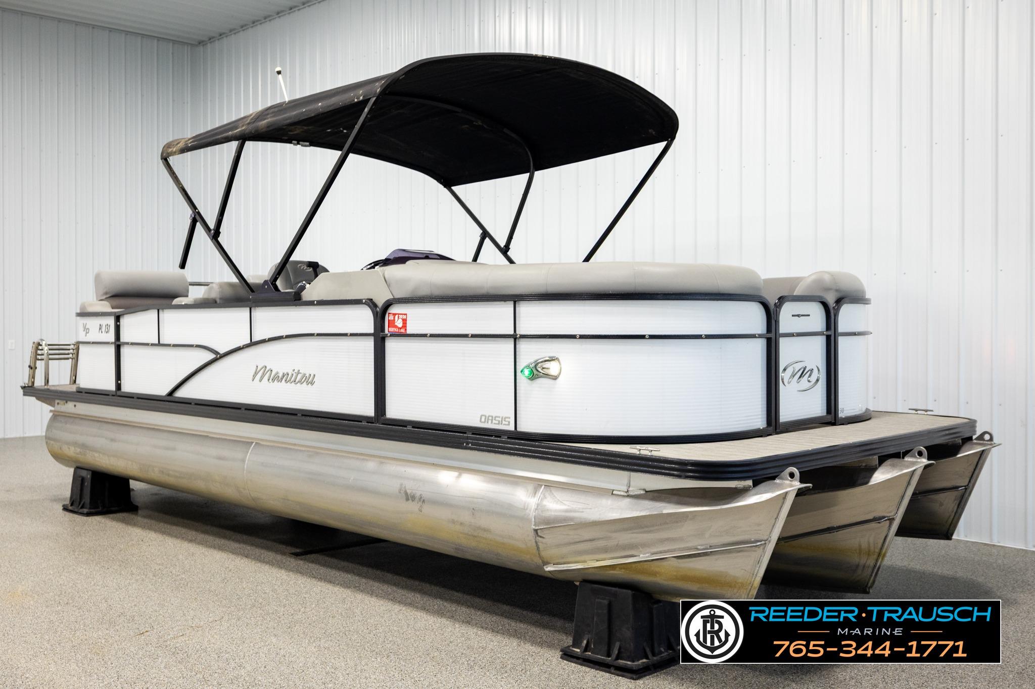 2019 Manitou Oasis SR VP pontoon boat with canopy in indoor showroom.