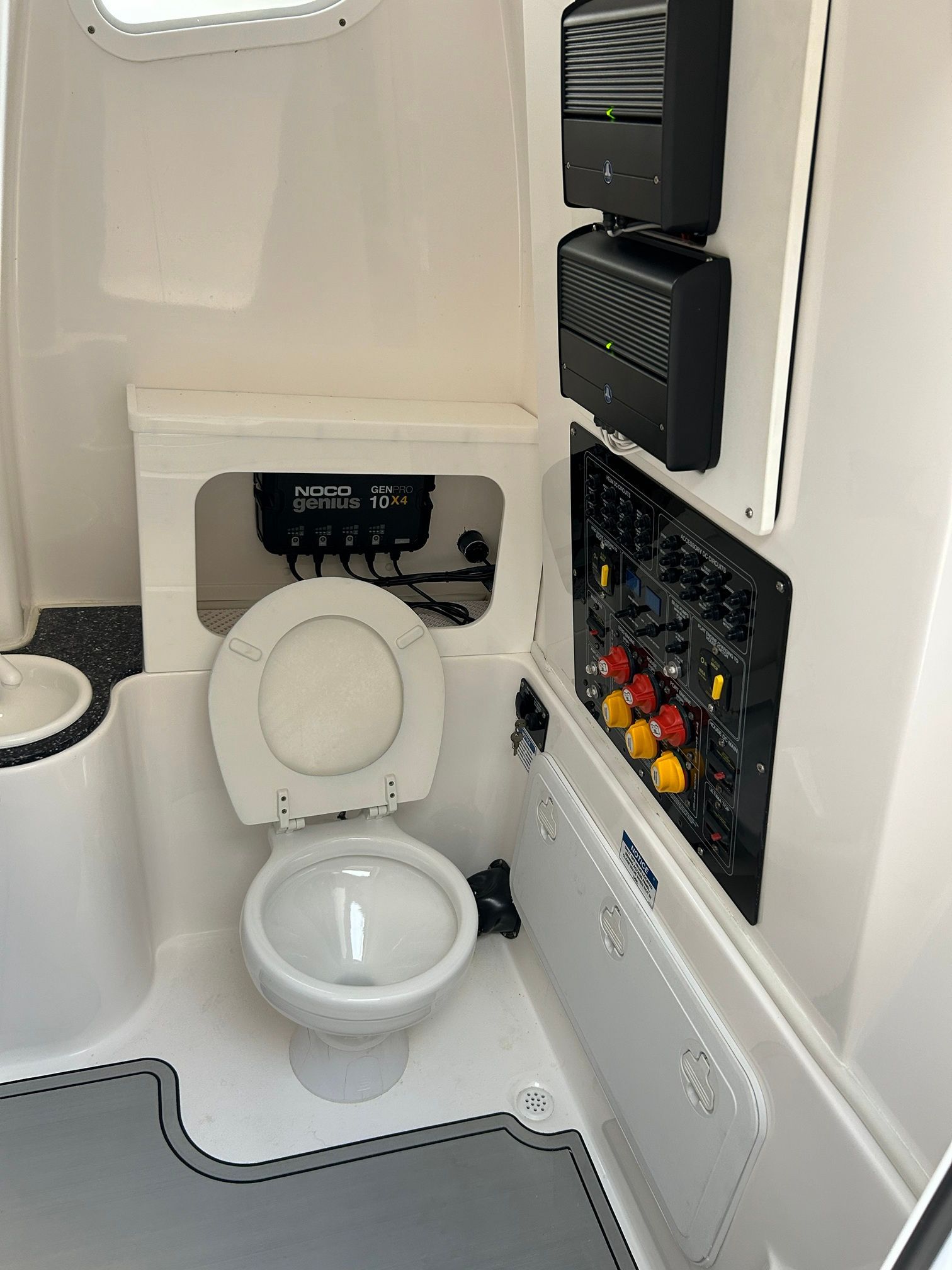 Interior view of a boat cabin with a toilet and control panel.