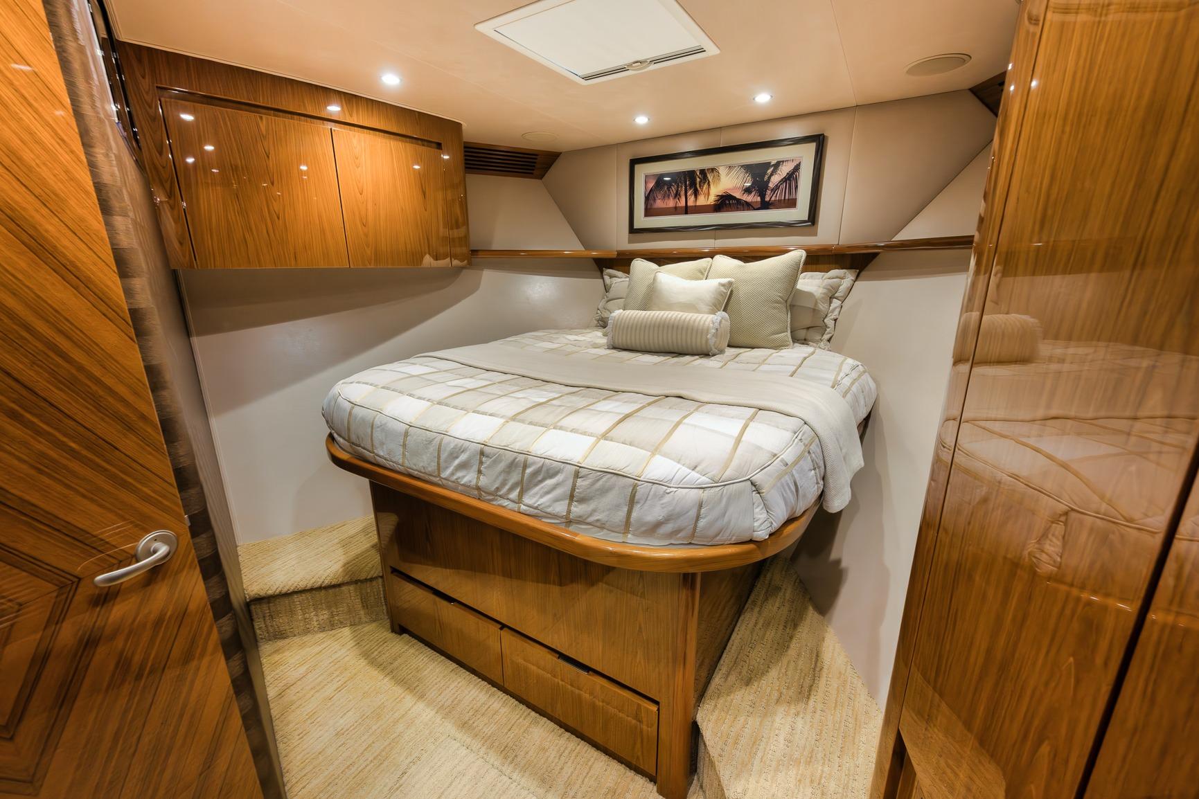 Luxurious bedroom interior of 2012 Viking 70 Enclosed Bridge yacht with wood finishes.