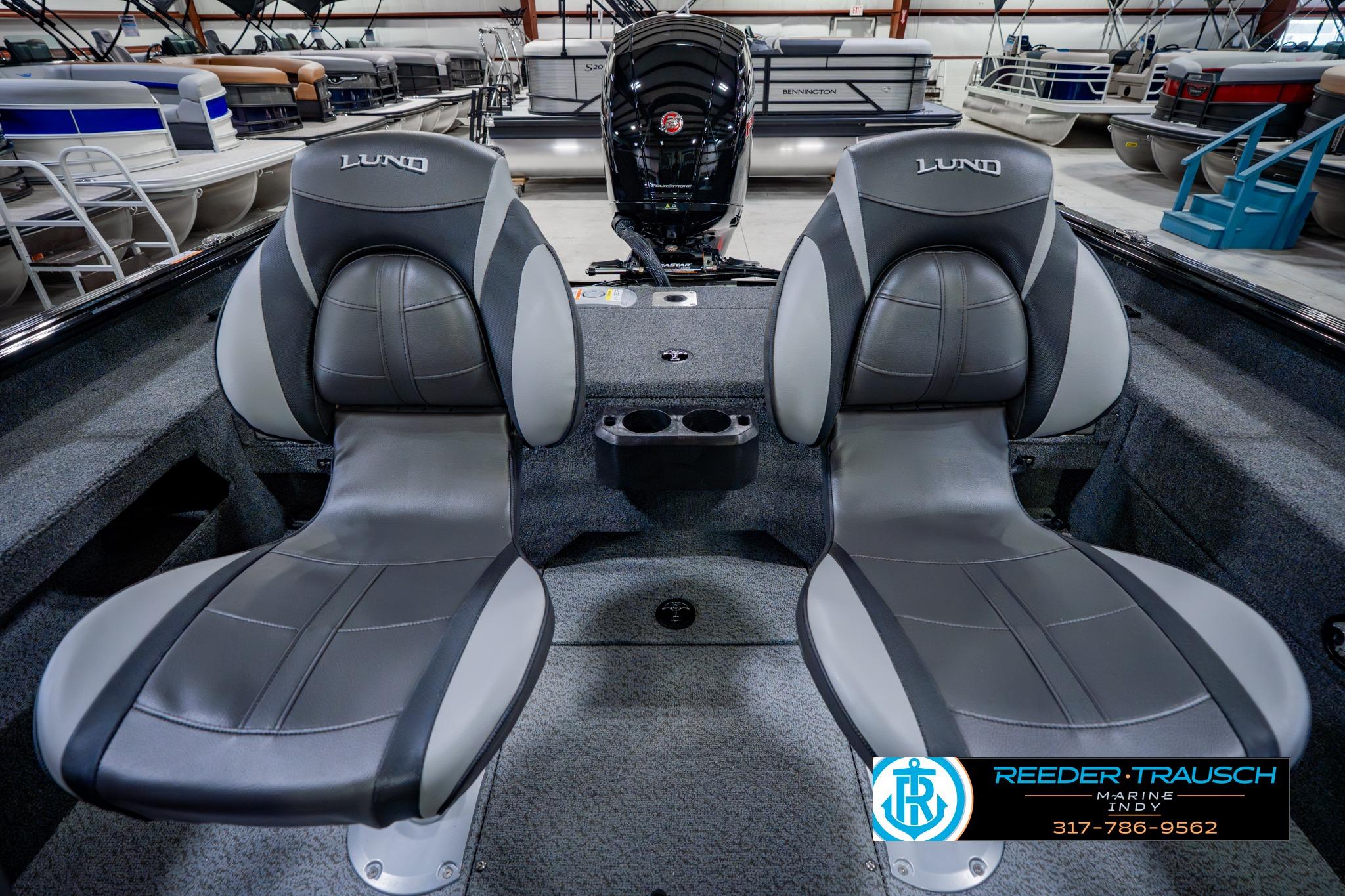 2026 Lund 1875 Impact XS boat interior with two gray seats and motor in showroom.