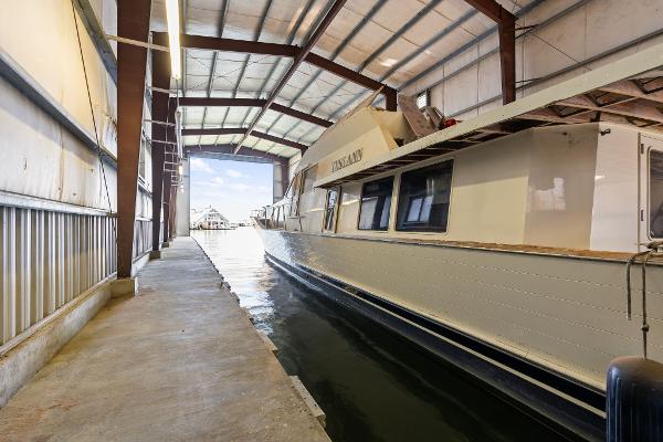 1985 Custom Larson Boathouse with boat docked inside, featuring metal roof and concrete walkway.