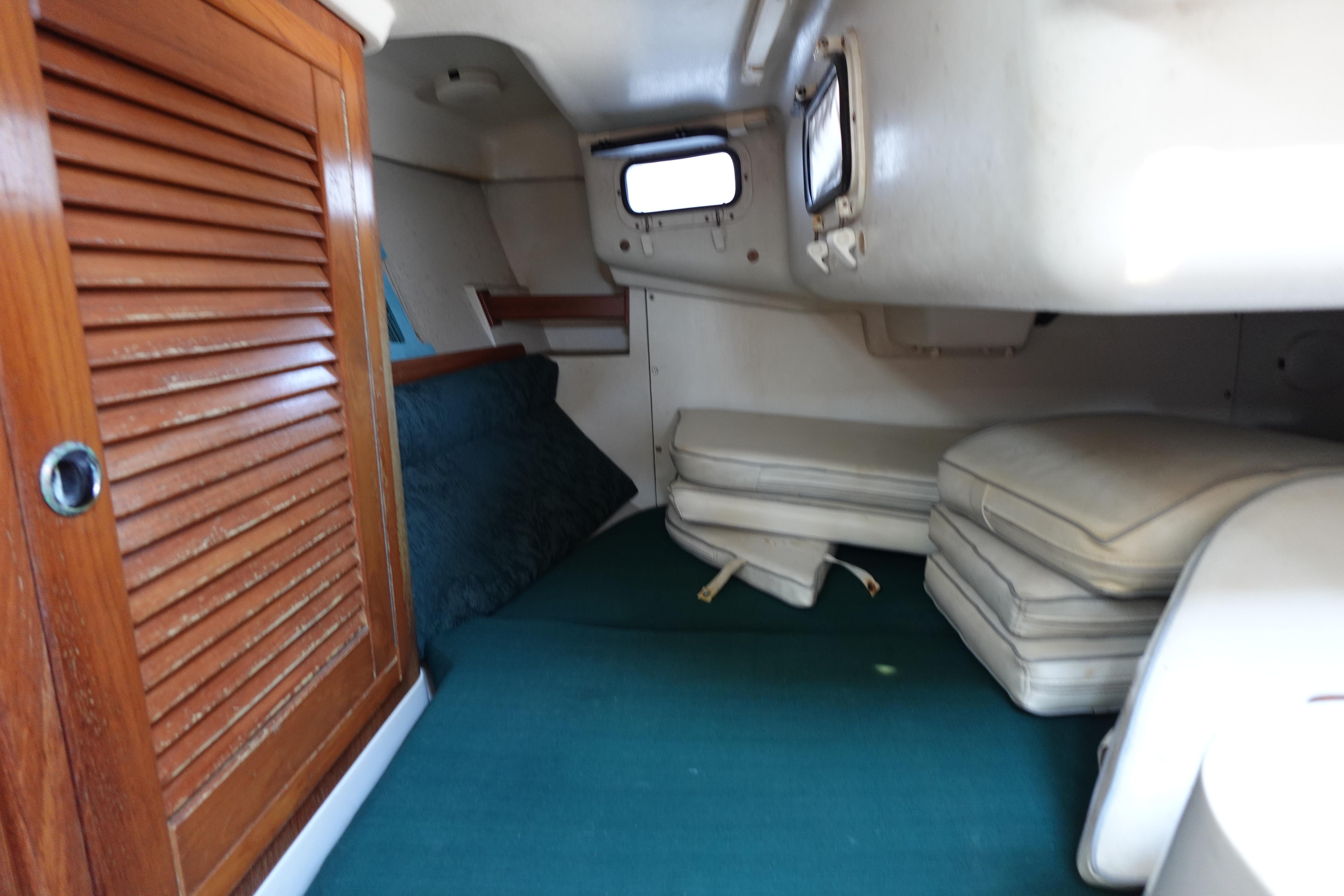 Interior cabin of a 1997 Catalina 28 sailboat with wooden door and cushions.