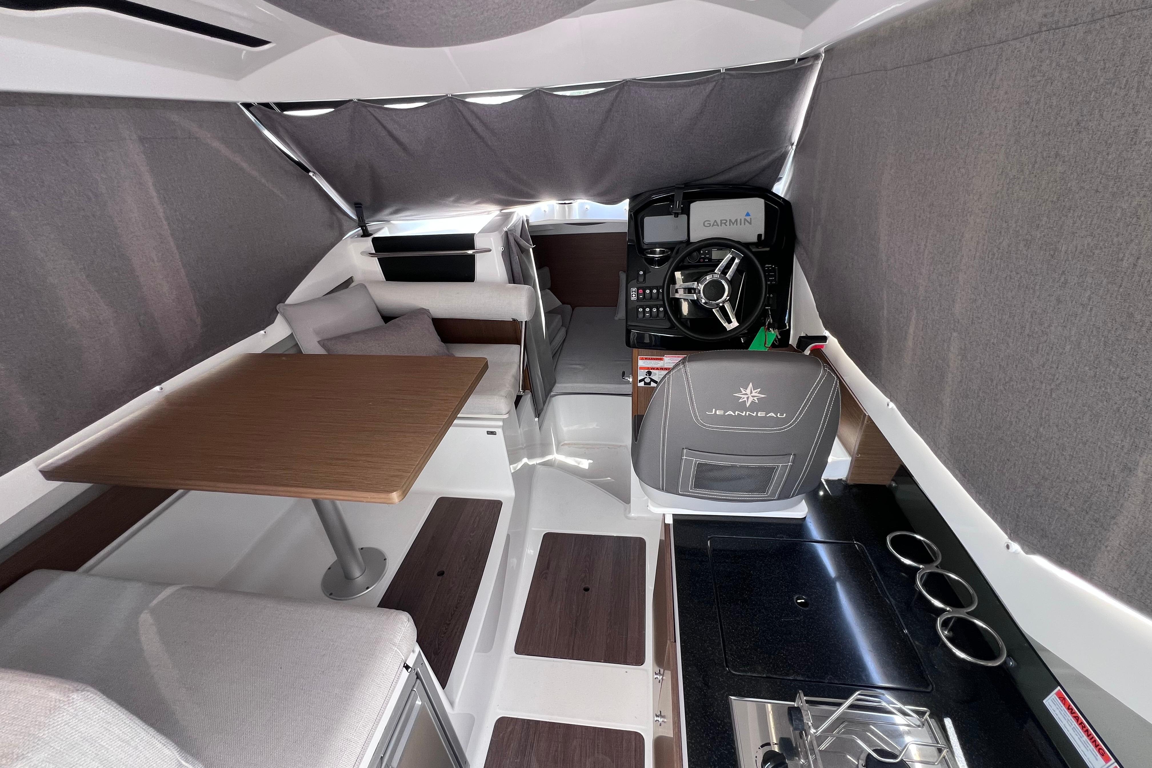 Interior of 2021 Jeanneau NC Weekender 795 Series 2 with helm, seating, and kitchenette.