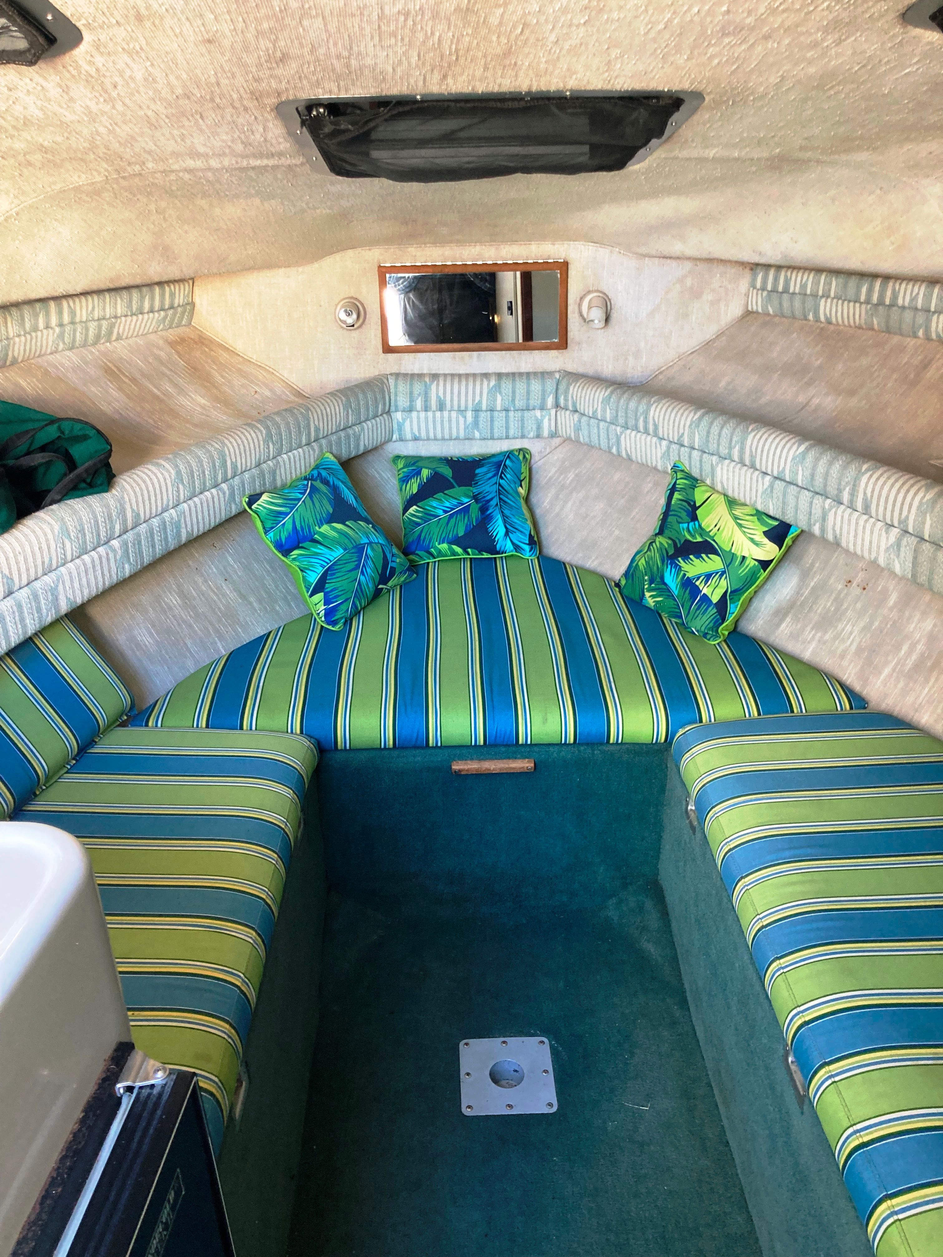 The interior of a 1991 Sea Ray 220 Sundancer features a cozy cabin with striped upholstery and tropical pillows.