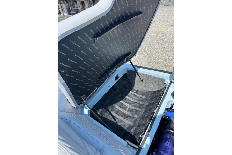 Open storage compartment of 2026 MasterCraft XStar 25 boat, showcasing interior details.