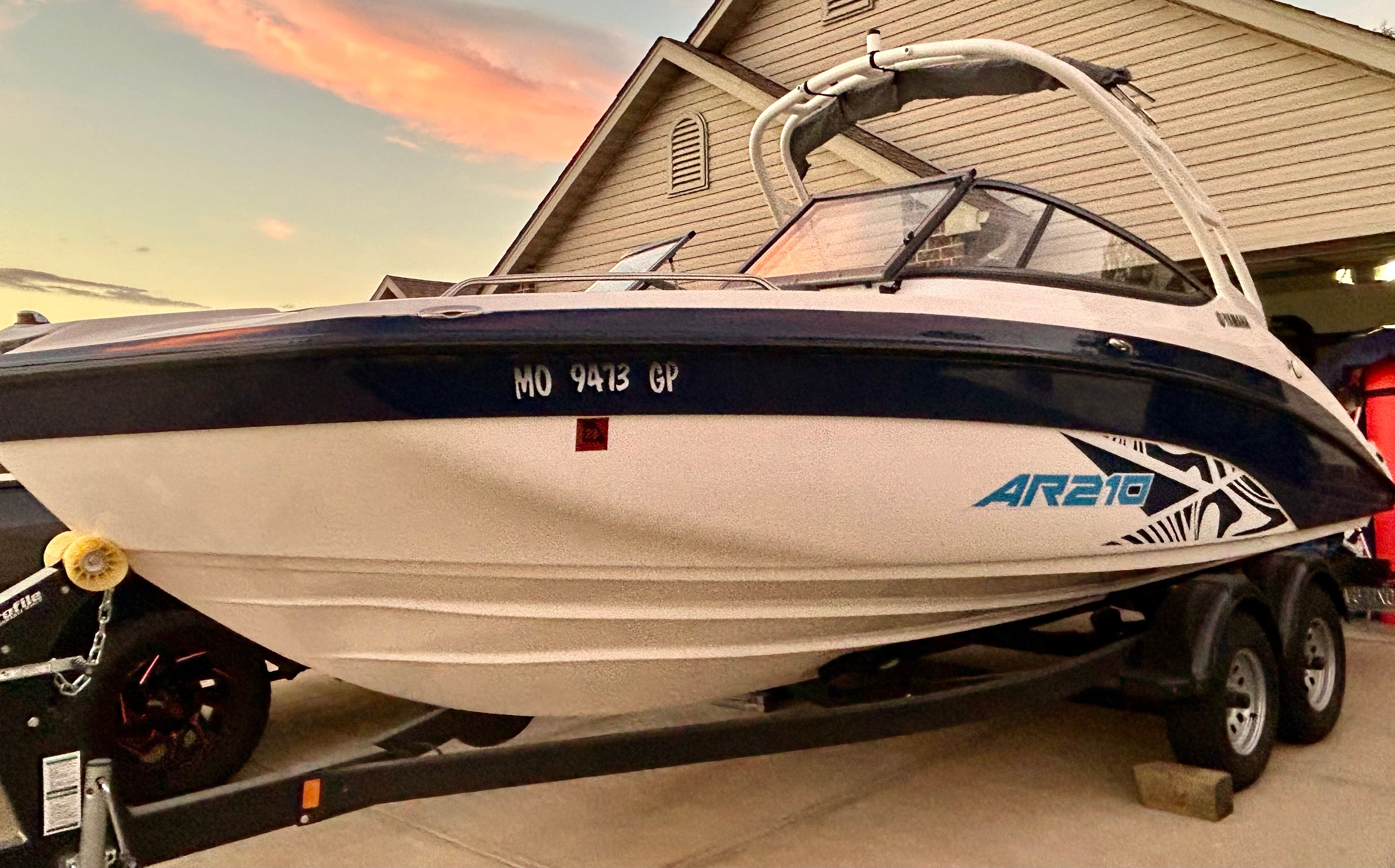 A 2022 Yamaha AR210 boat is on a trailer in front of a house.