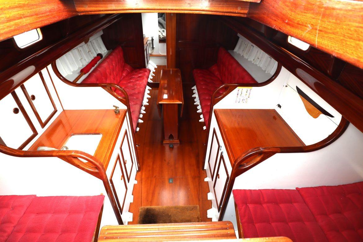 Interior of a 1939 Classic Custom boat with red cushioned seating and wooden cabinetry.