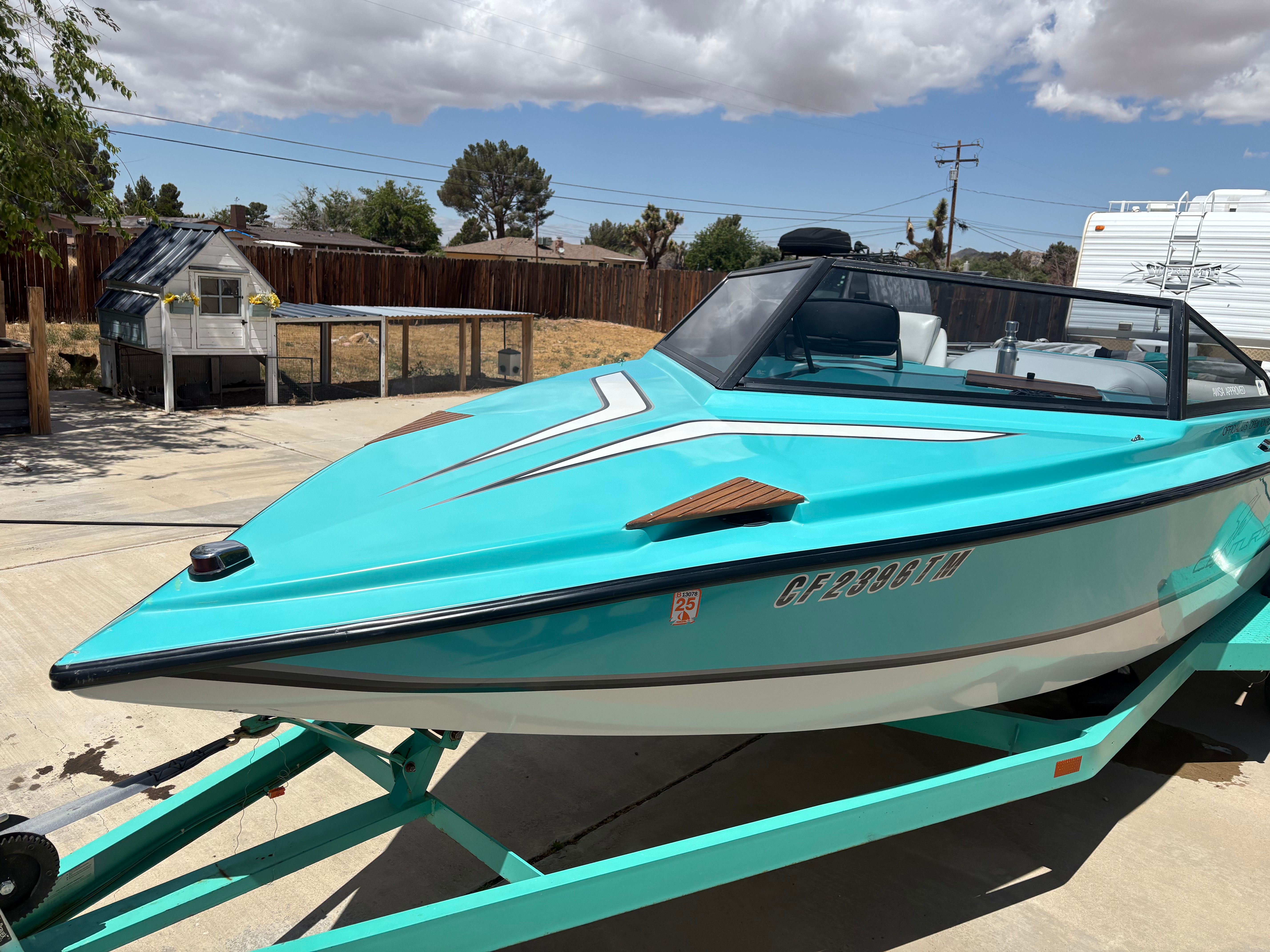 A turquoise 1991 Ski Centurion Falcon boat on a trailer outdoors.