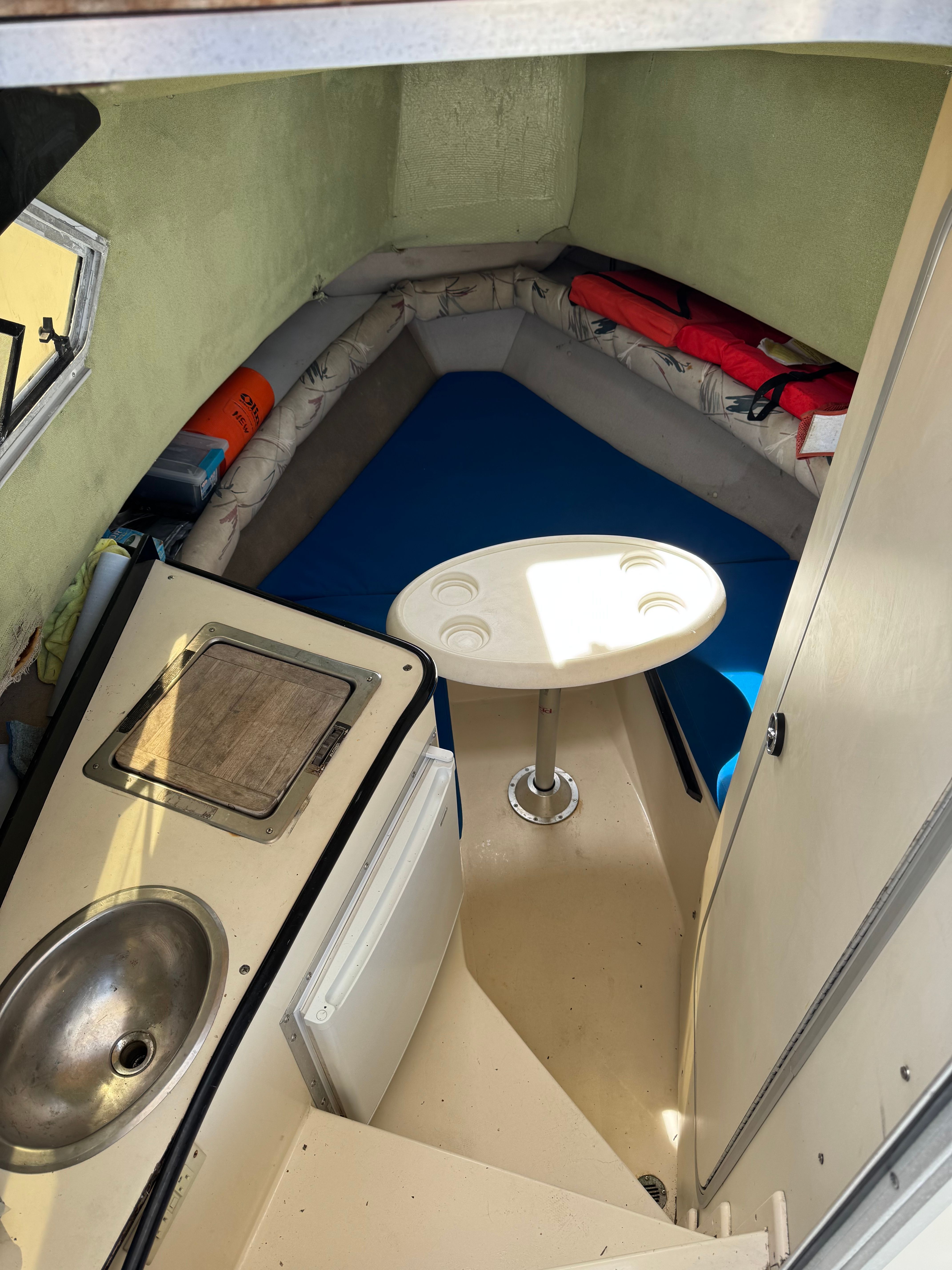 Interior of a boat with a table, sink, and seating area.