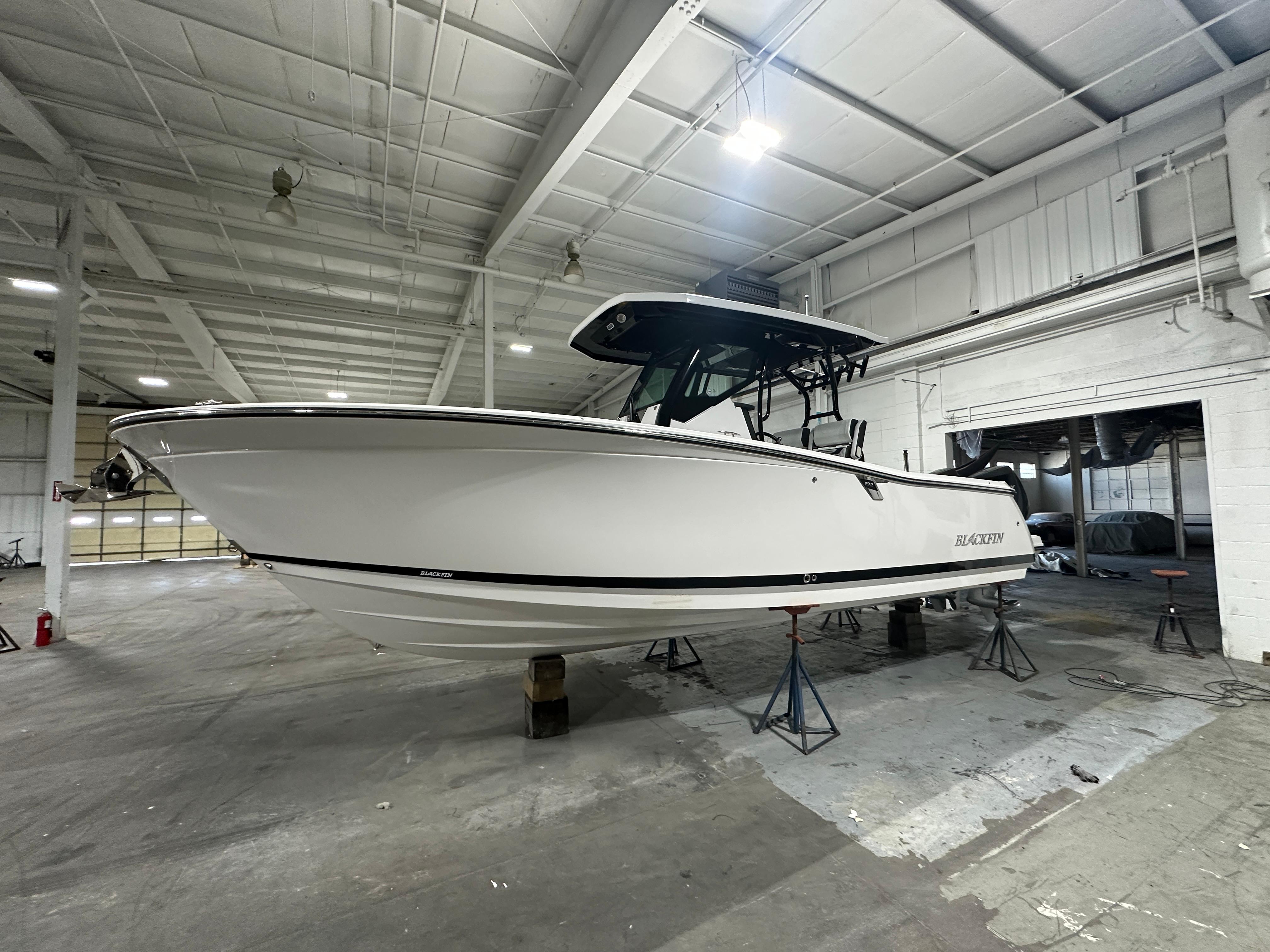 2025 Blackfin 272CC boat in a warehouse, elevated on stands.