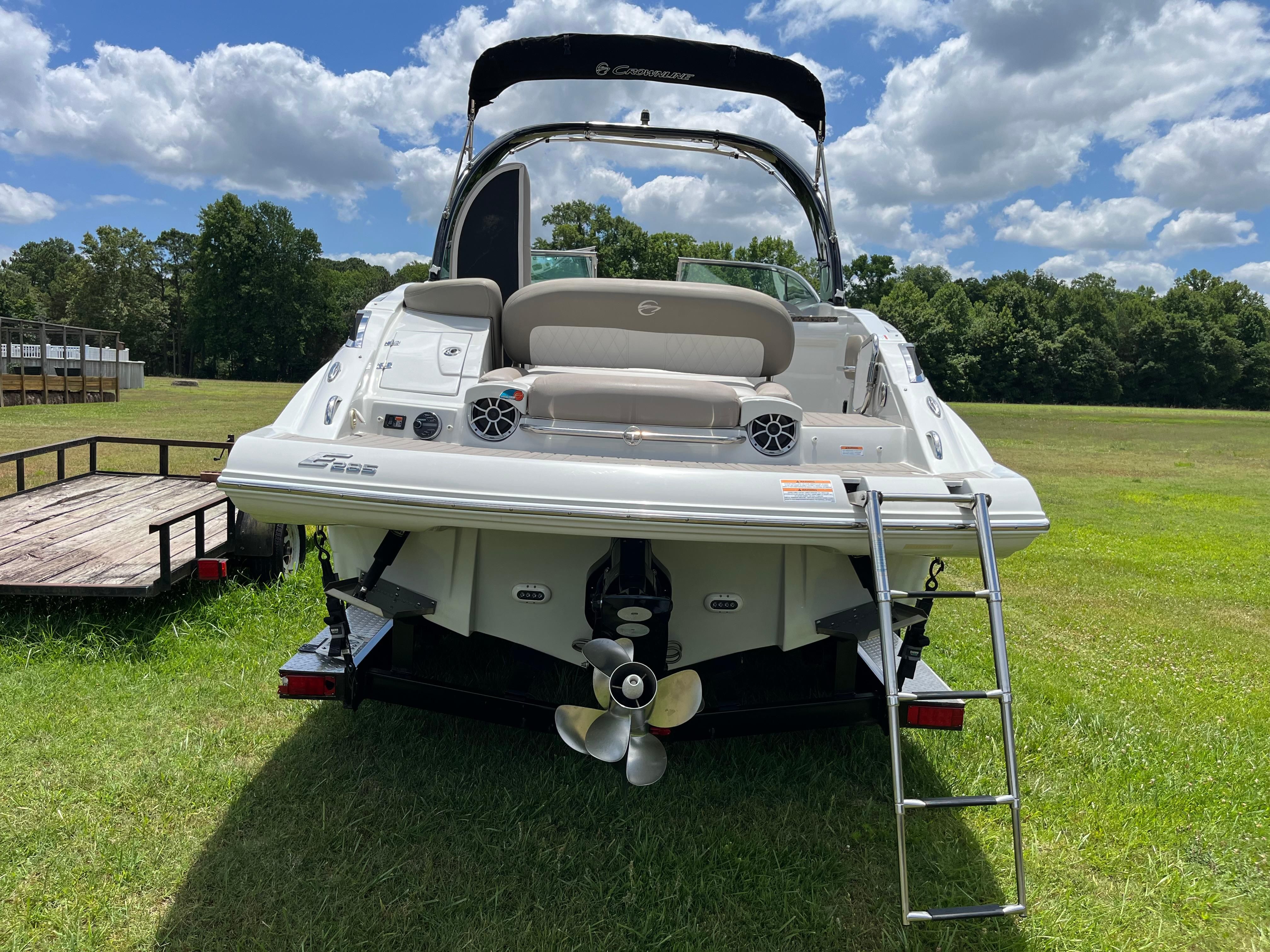 The image shows a 2019 Crownline E 285 boat on a trailer in a grassy field.