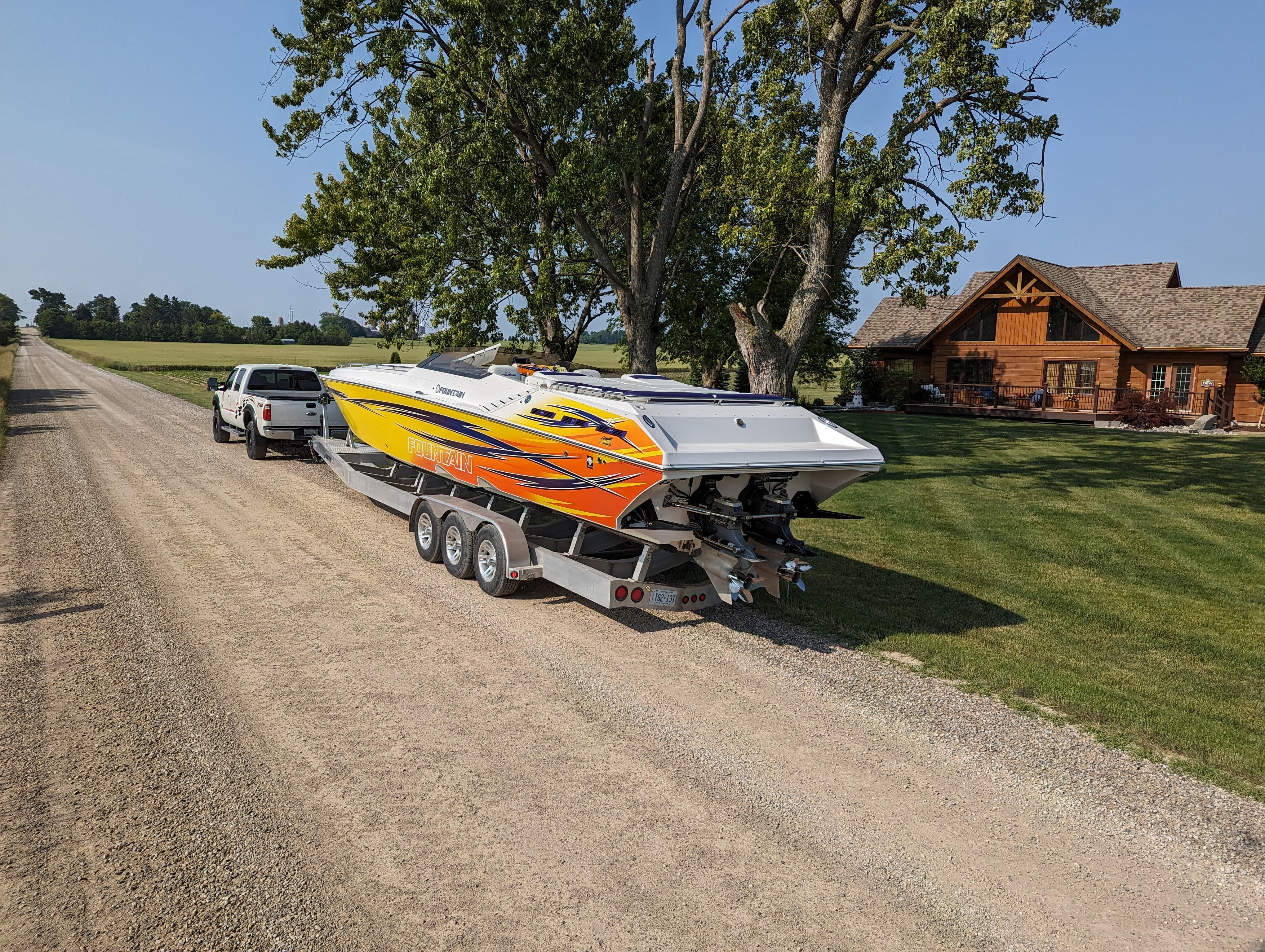A 2006 Fountain 42 speedboat on a trailer, parked on a rural gravel road.