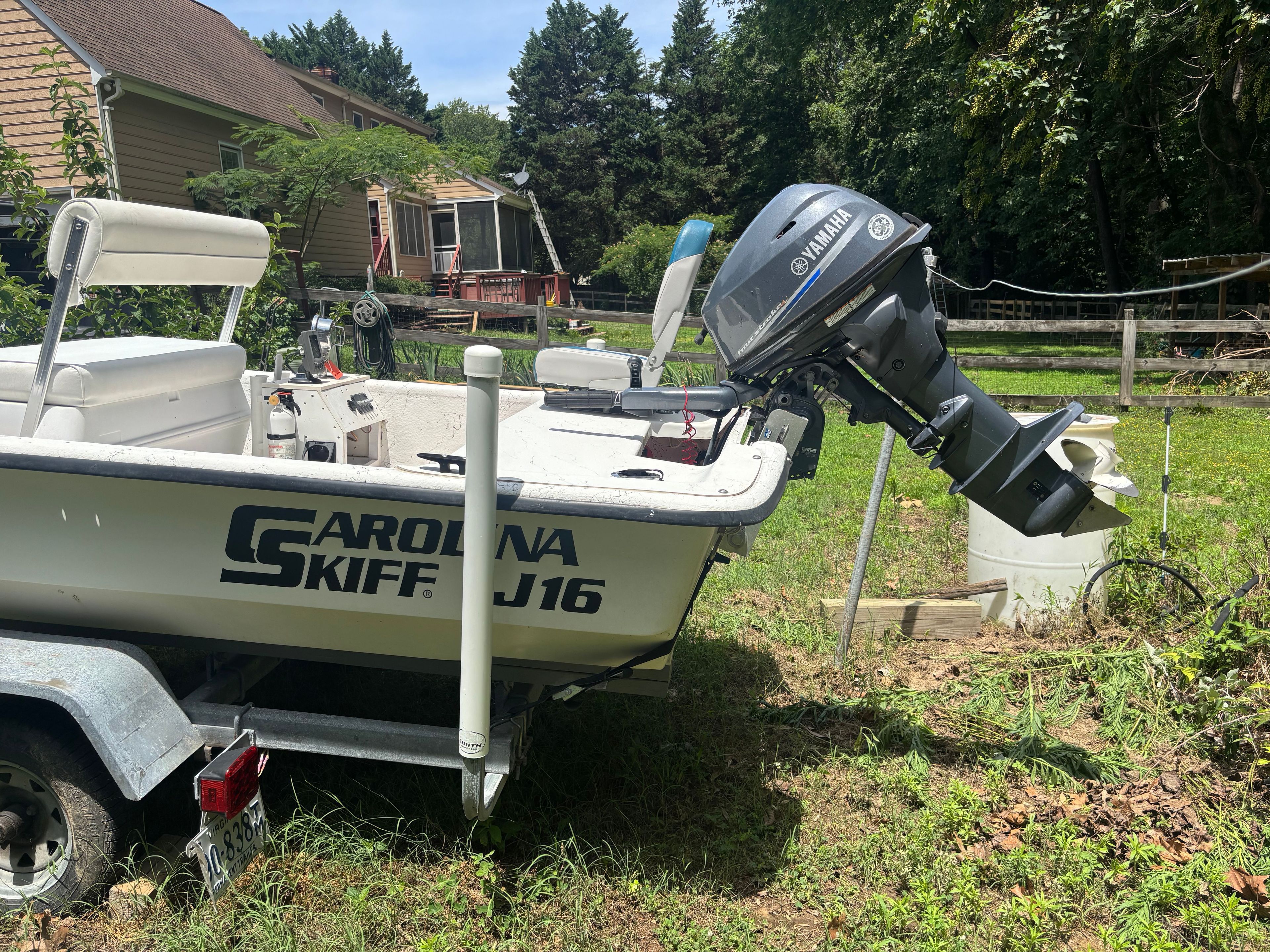 A 2004 Carolina Skiff J16 boat on a trailer in a garden setting.