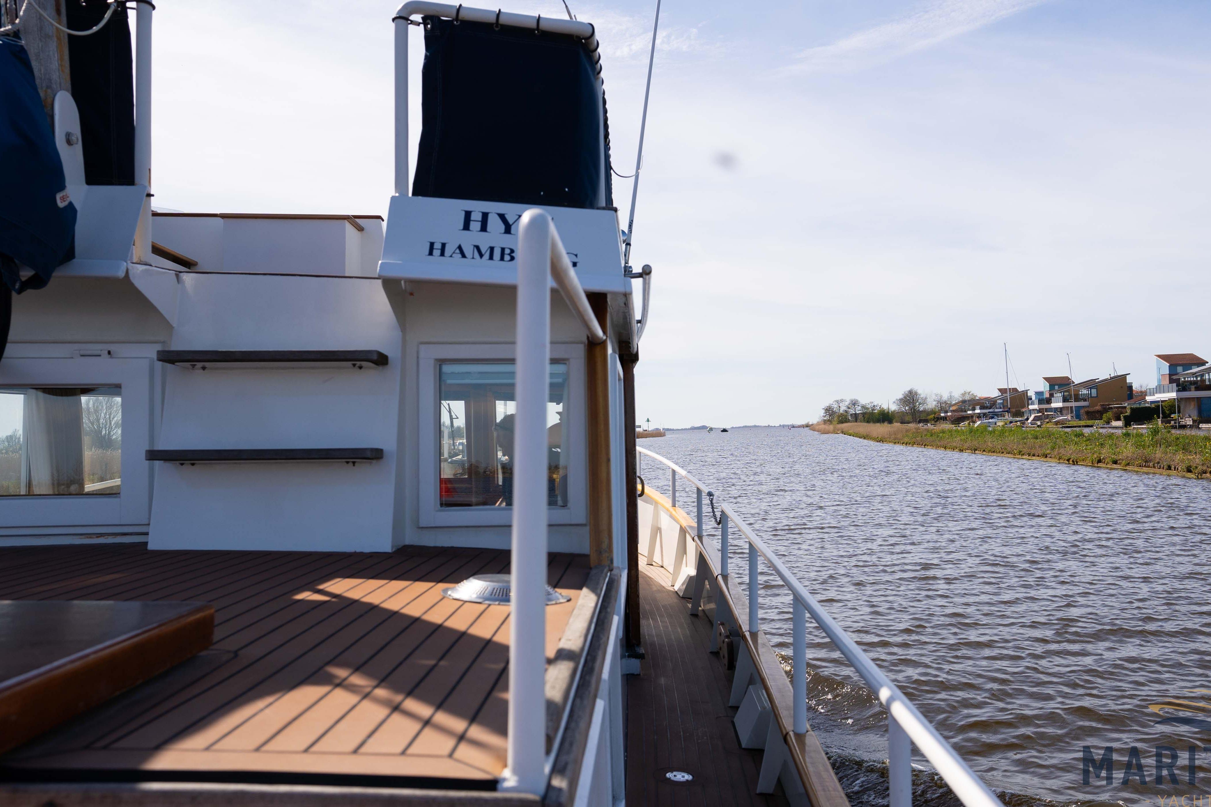 Elbtrawler 1095 (1996) cruising on a serene river with clear skies.